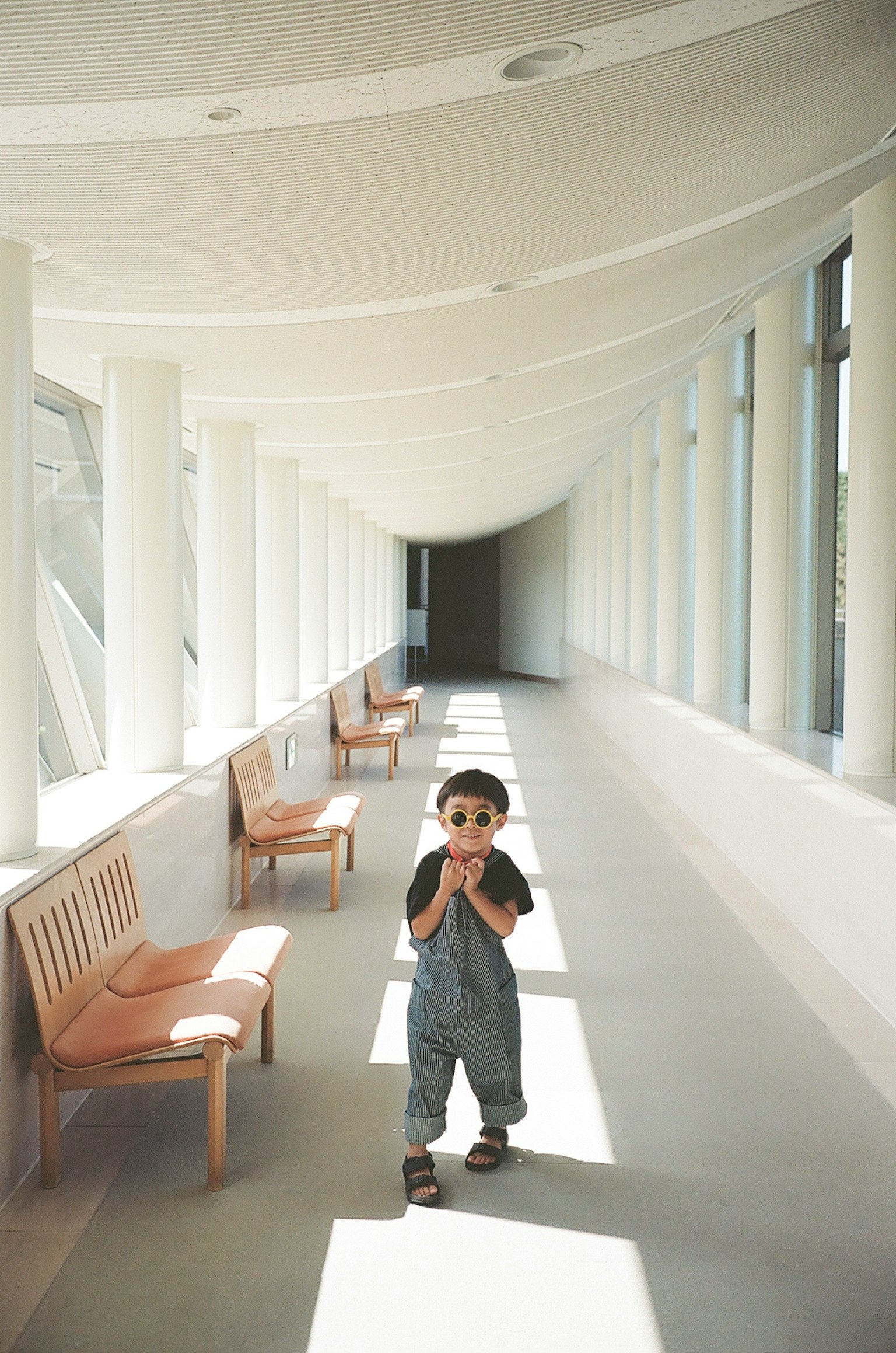 Un niño caminando en un pasillo con columnas blancas y bancos