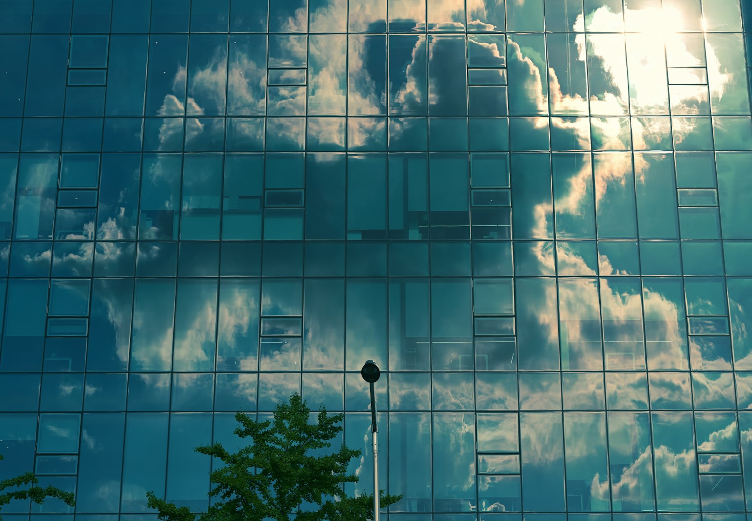 Reflejo de nubes y luz solar en un edificio de vidrio azul