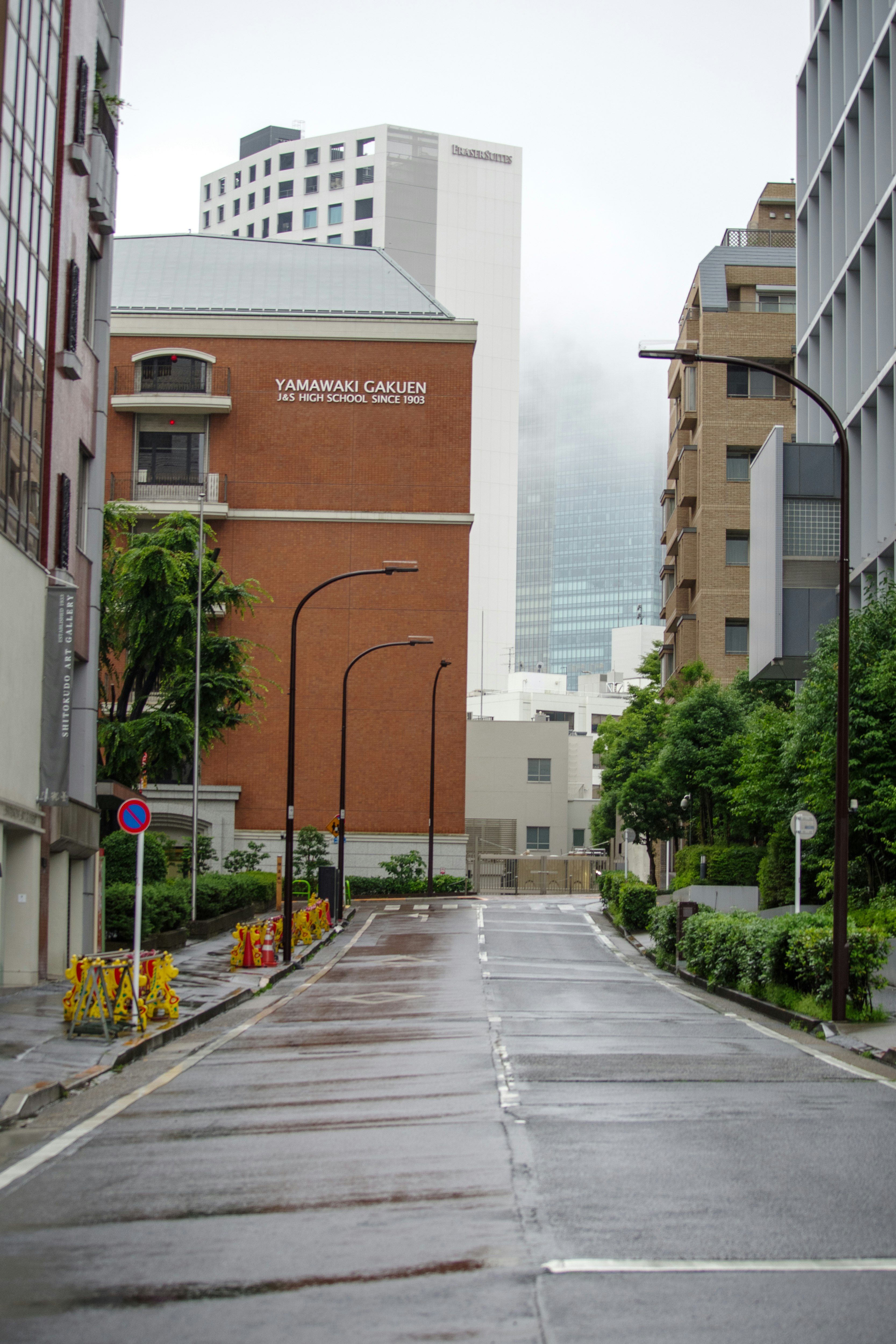 霧のかかった都心の路地に並ぶビル群の通り画像