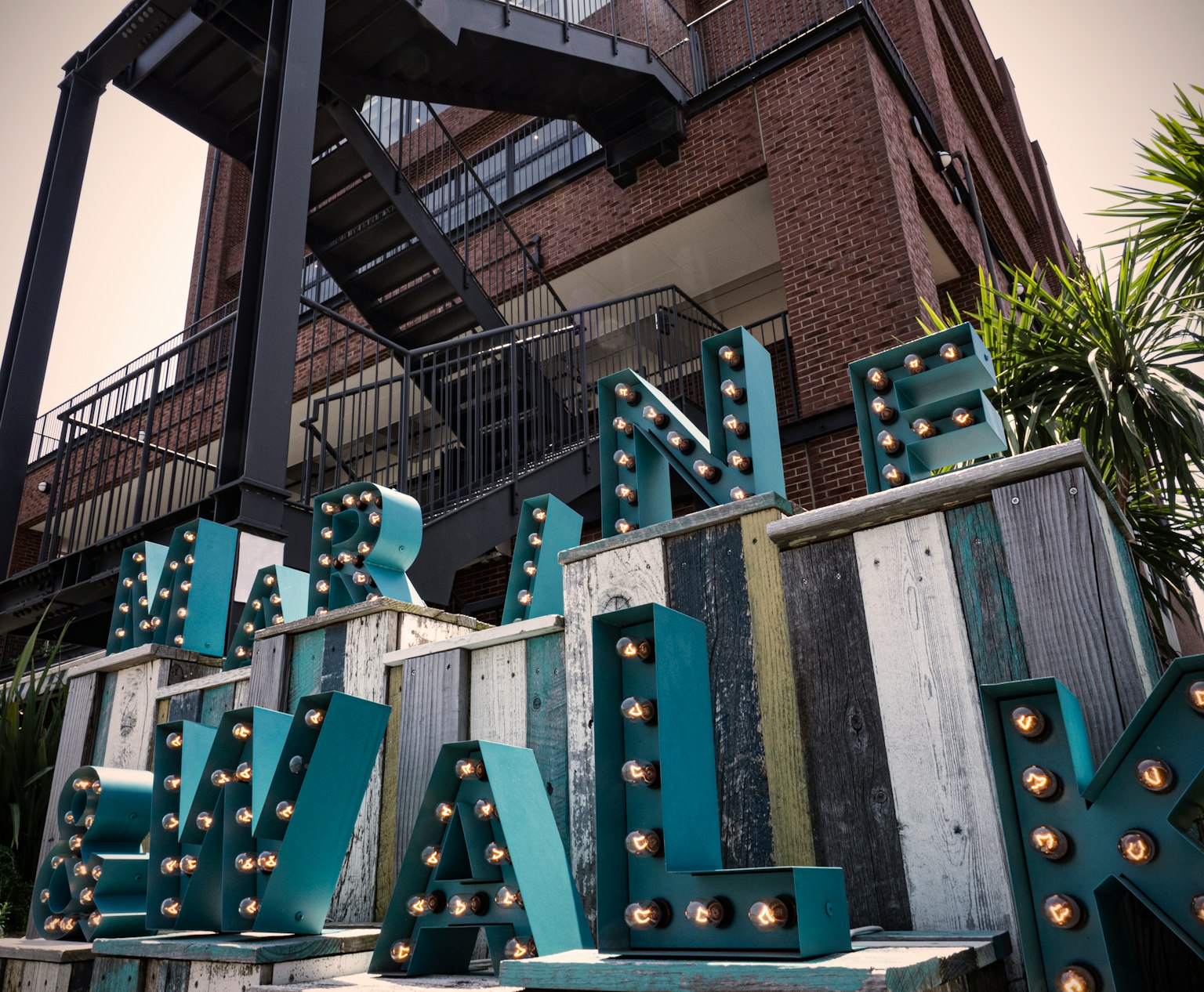 Colorful illuminated letters spelling Marina Walk in front of a building with a staircase
