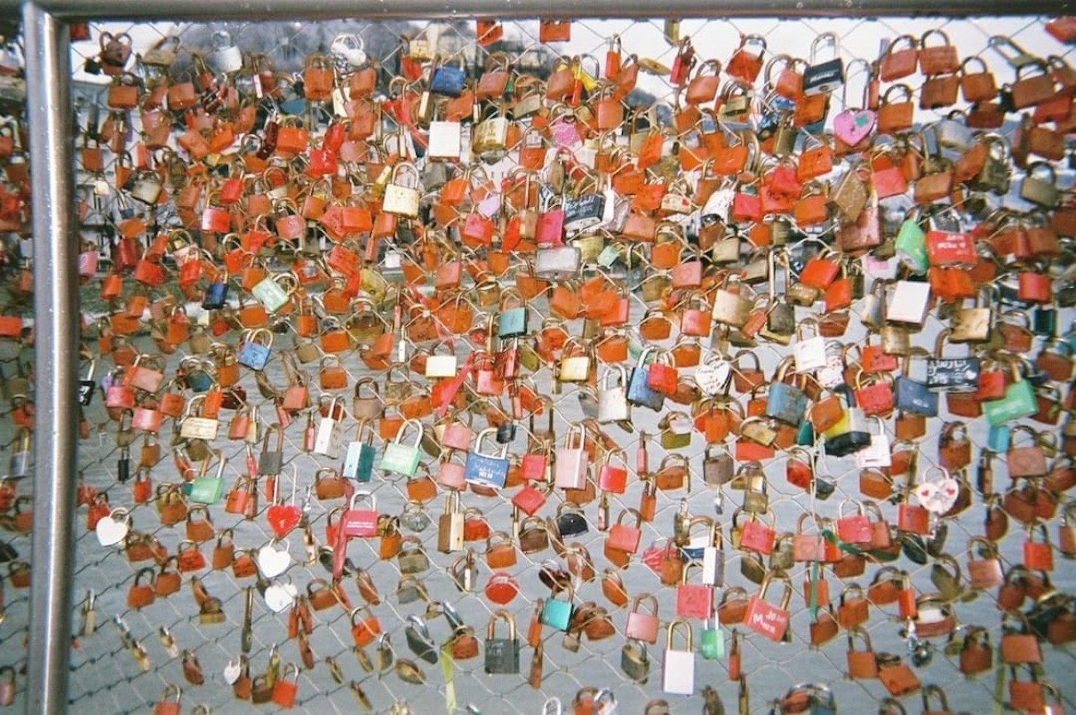 Eine Sammlung von bunten Vorhängeschlössern, die an einem Zaun befestigt sind