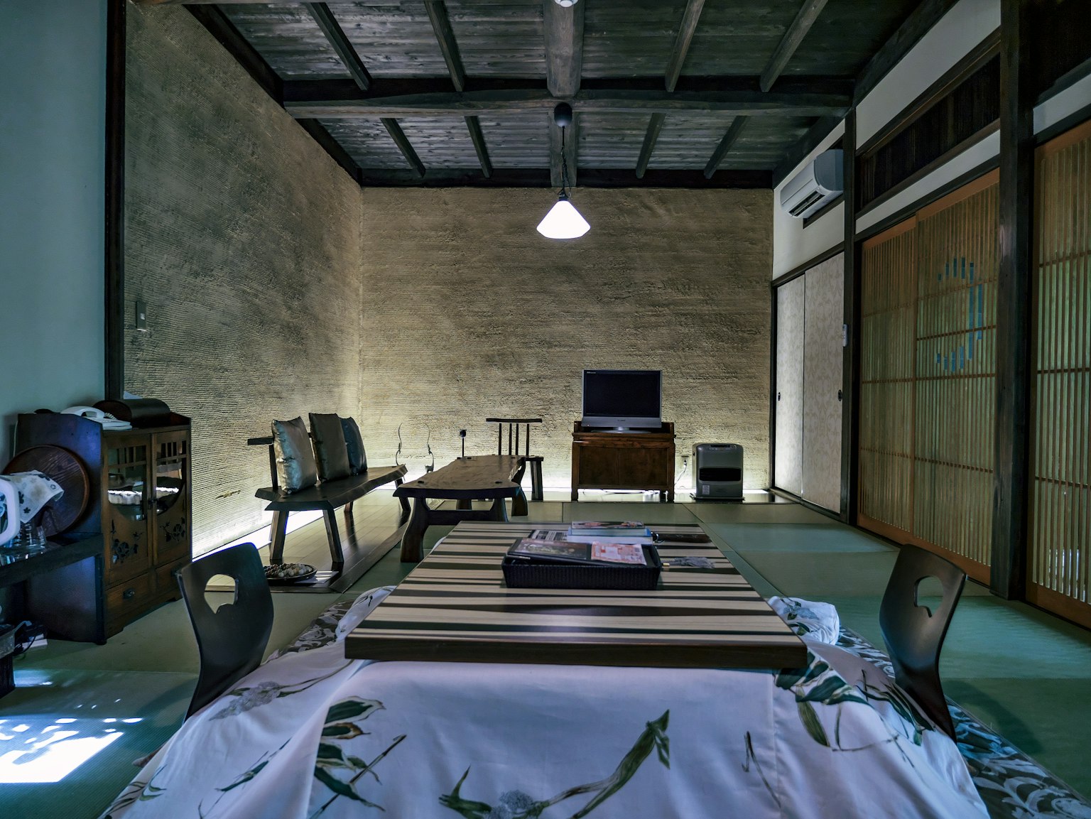 Einfaches Interieur eines japanischen Zimmers mit Holztisch und Stühlen Fernseher und traditioneller Dekoration