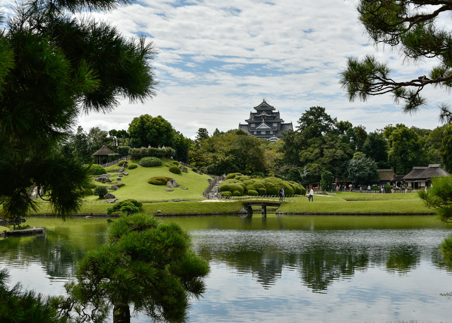 宁静的池塘反射出美丽花园的风景，背景有一座日本城堡