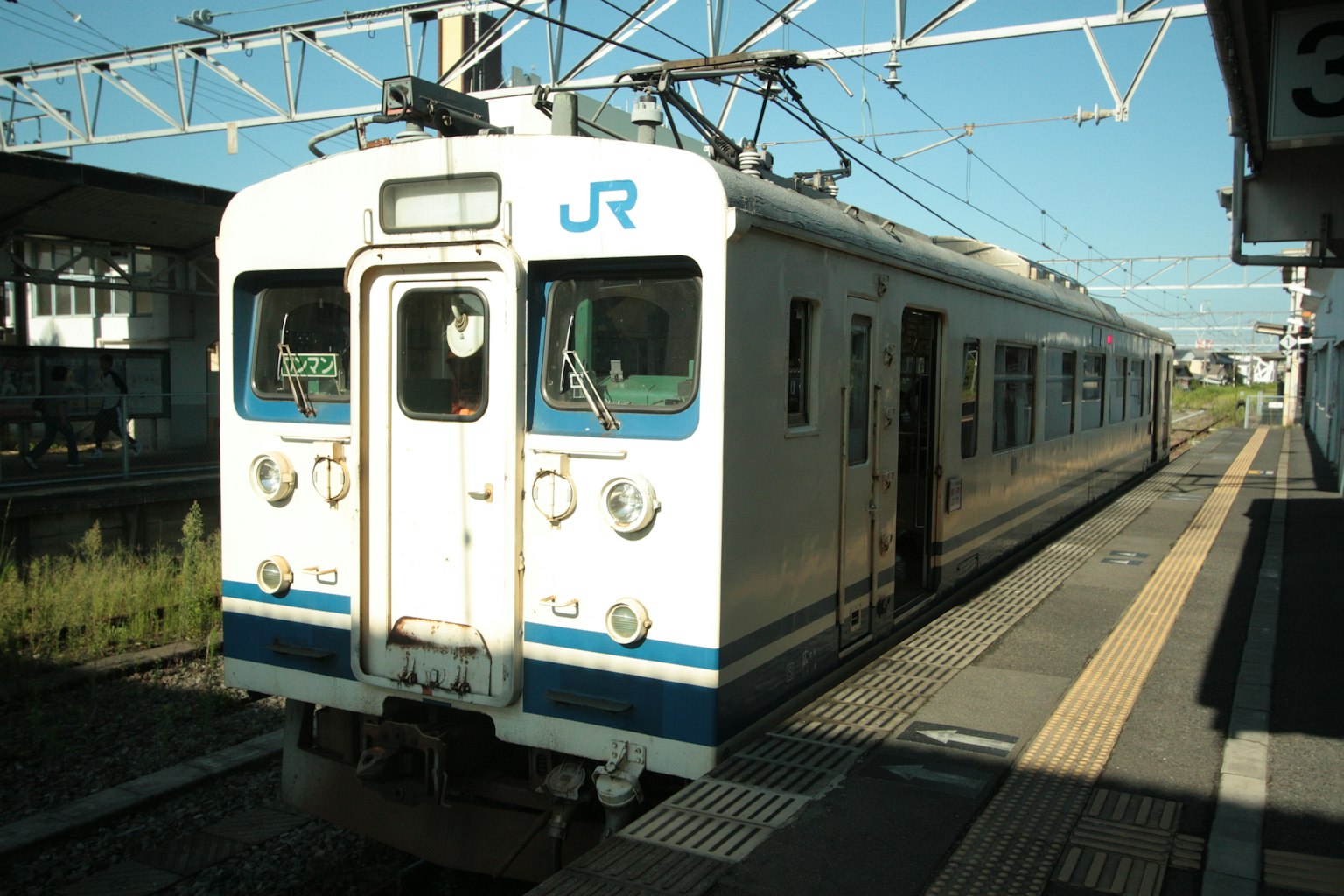 Tren JR blanco detenido en la estación bajo un cielo azul