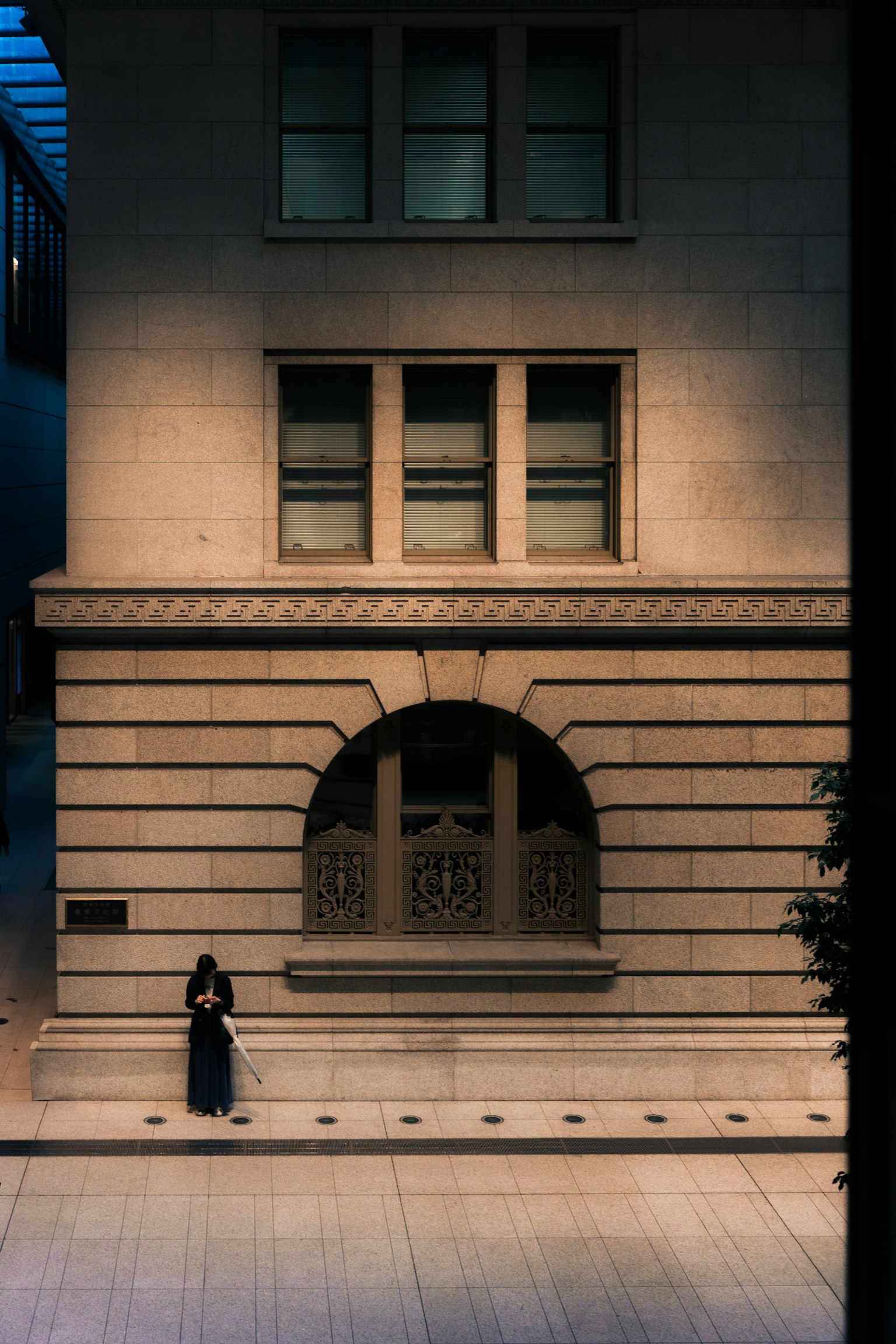 Una donna seduta davanti a un edificio con una bella illuminazione e un design delle finestre