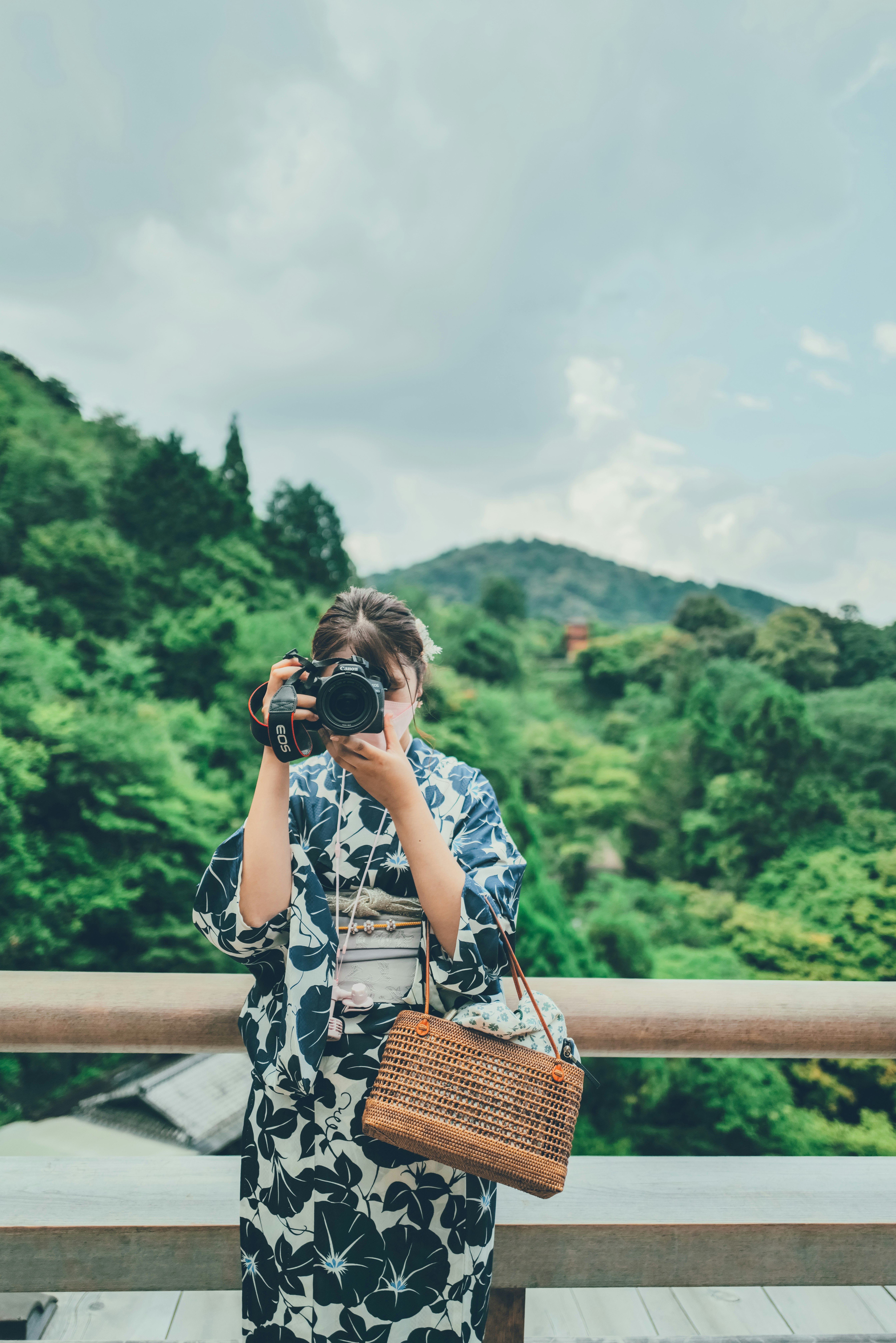 donna con macchina fotografica su un belvedere davanti a colline verdi