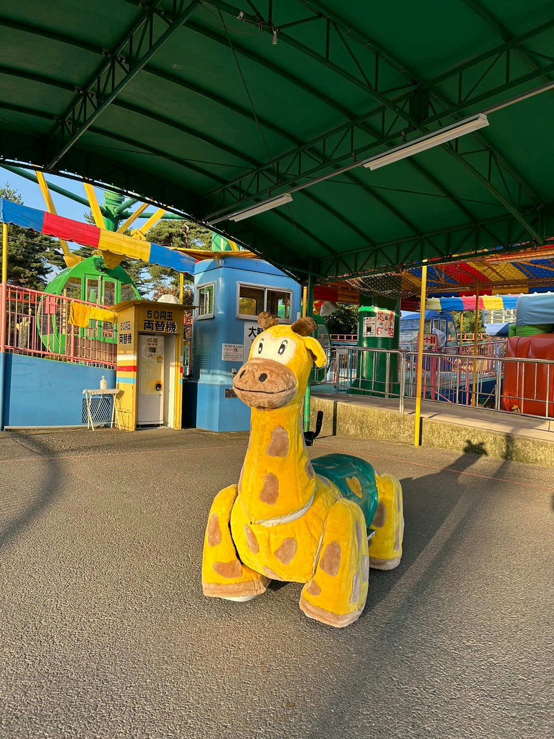 yellow character statue in a playground area under a green canopy