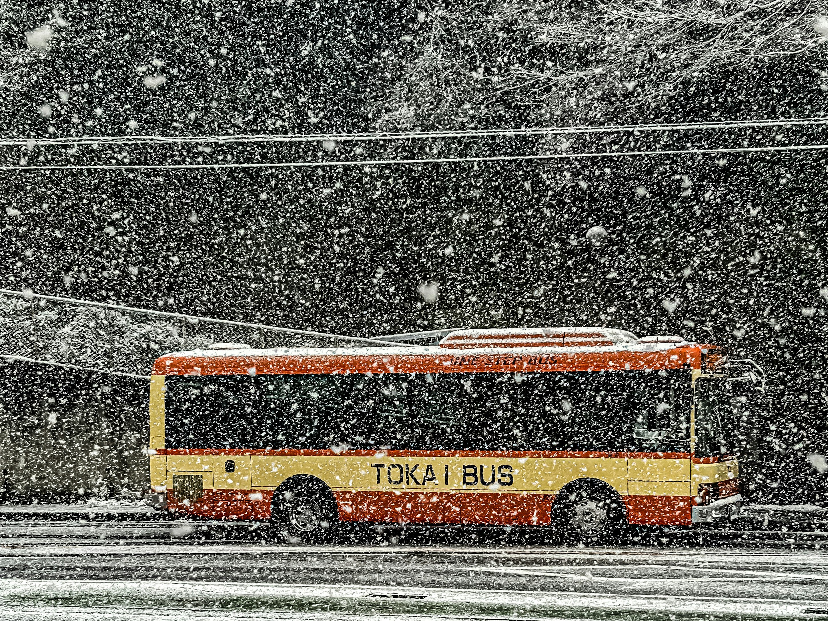 雪の中を走るバスの風景 バスは赤と黄色のカラーリング