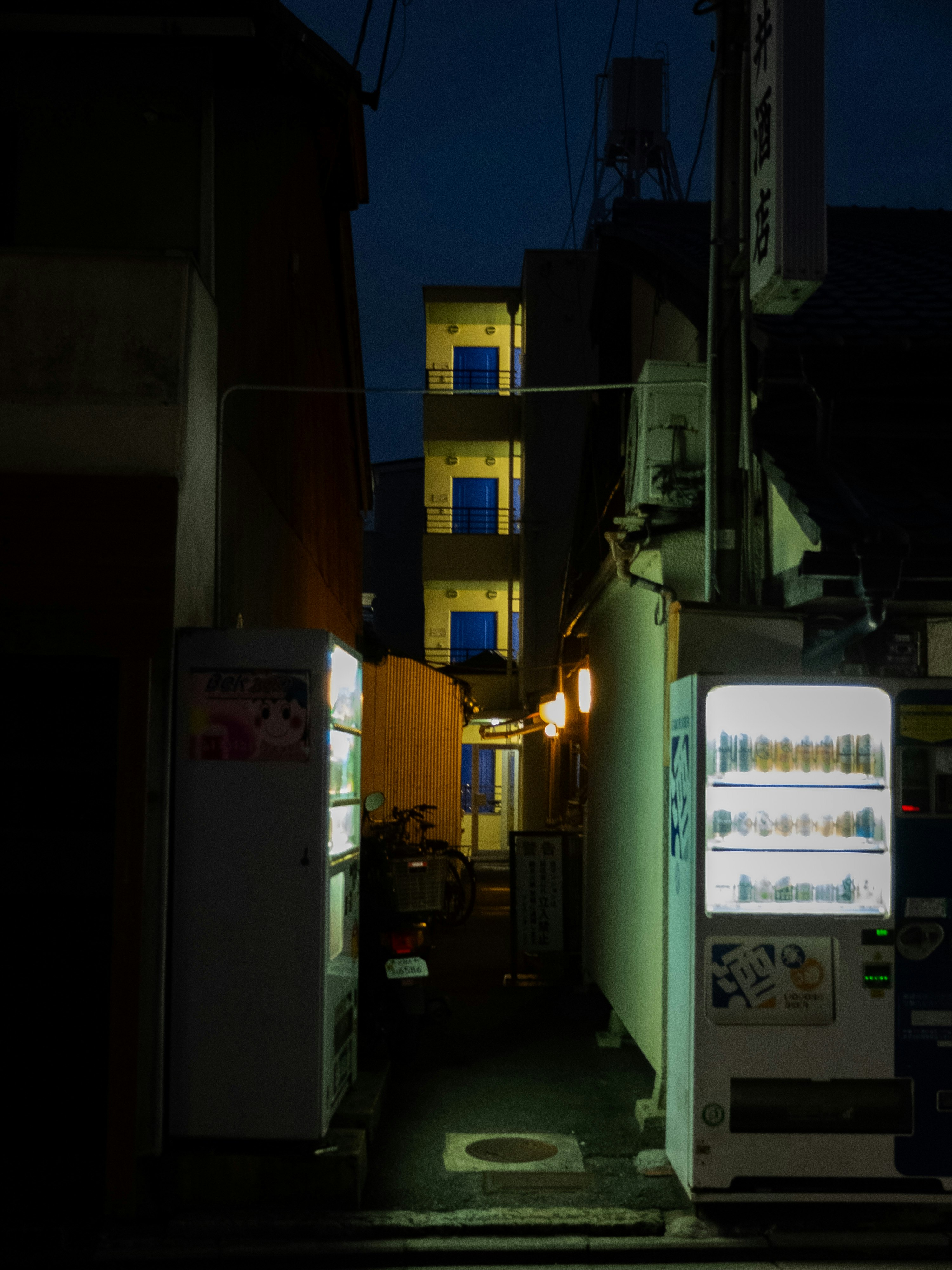 路地の夜に光る自販機と建物の間