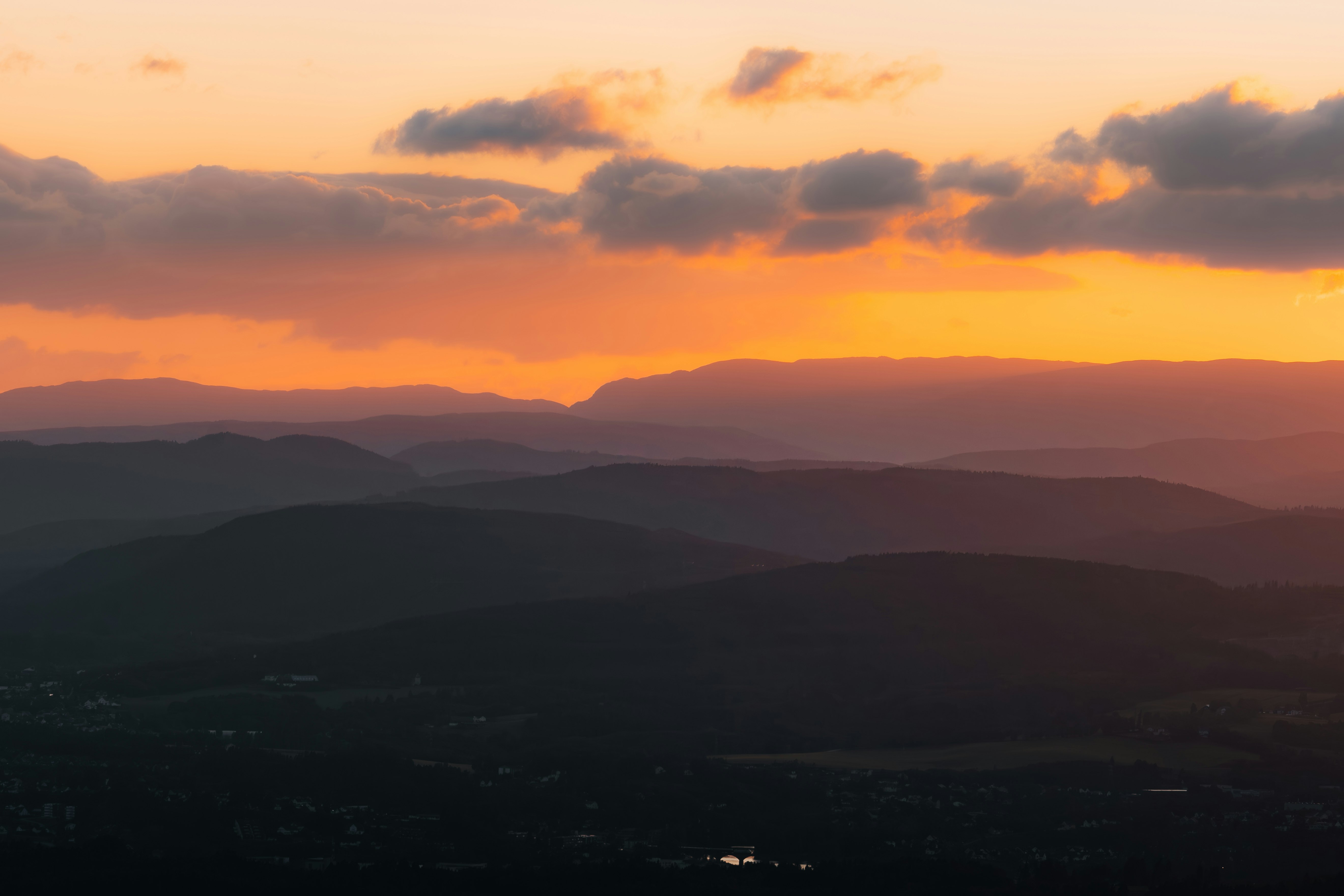 夕焼けの山並みと雲のシルエットが広がる風景