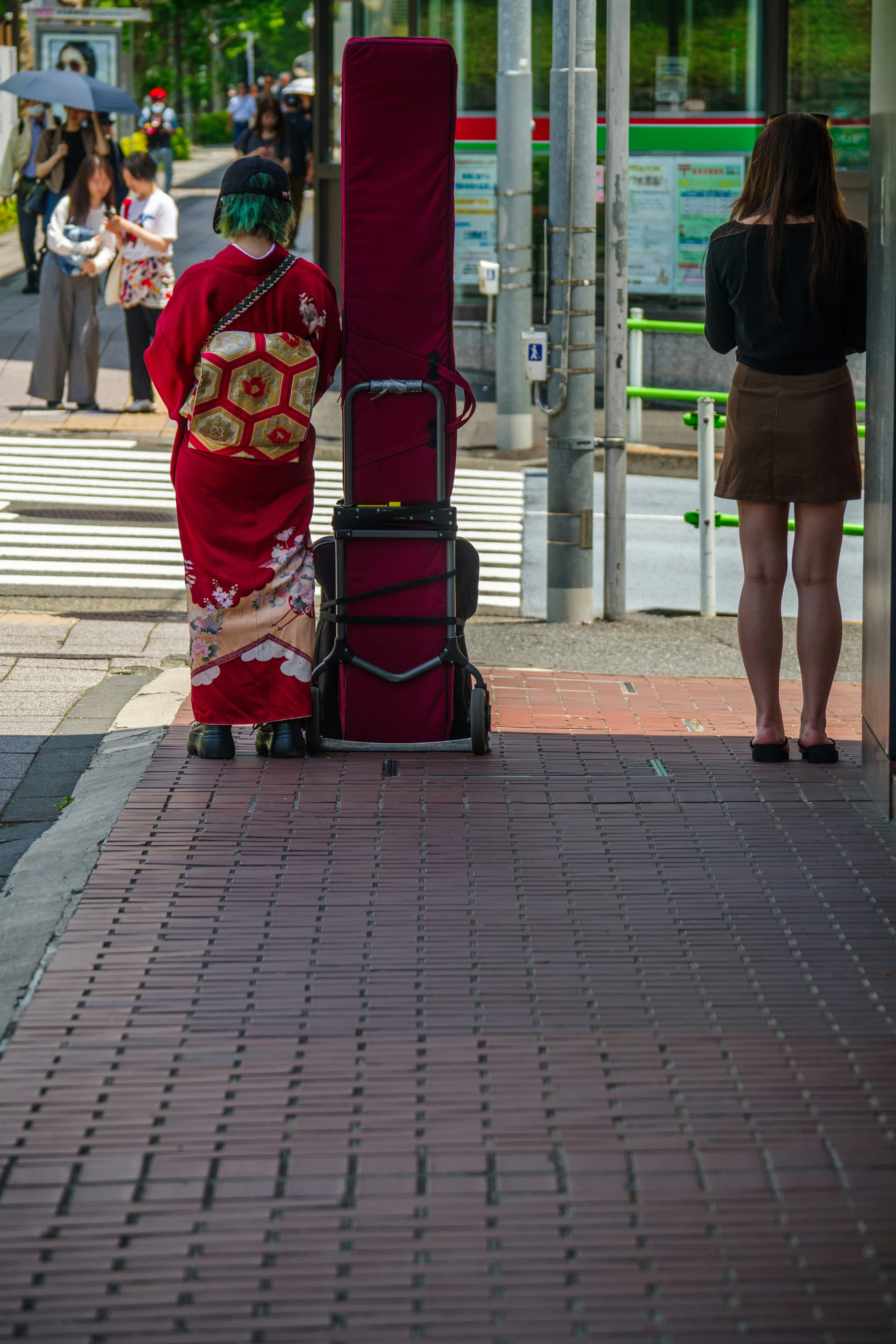 Travelers waiting with suitcases on a shaded city sidewalk