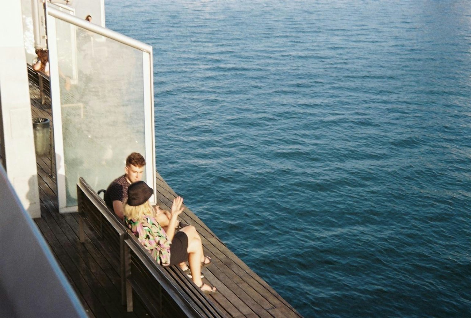 海の近くのベンチに座るカップルの写真