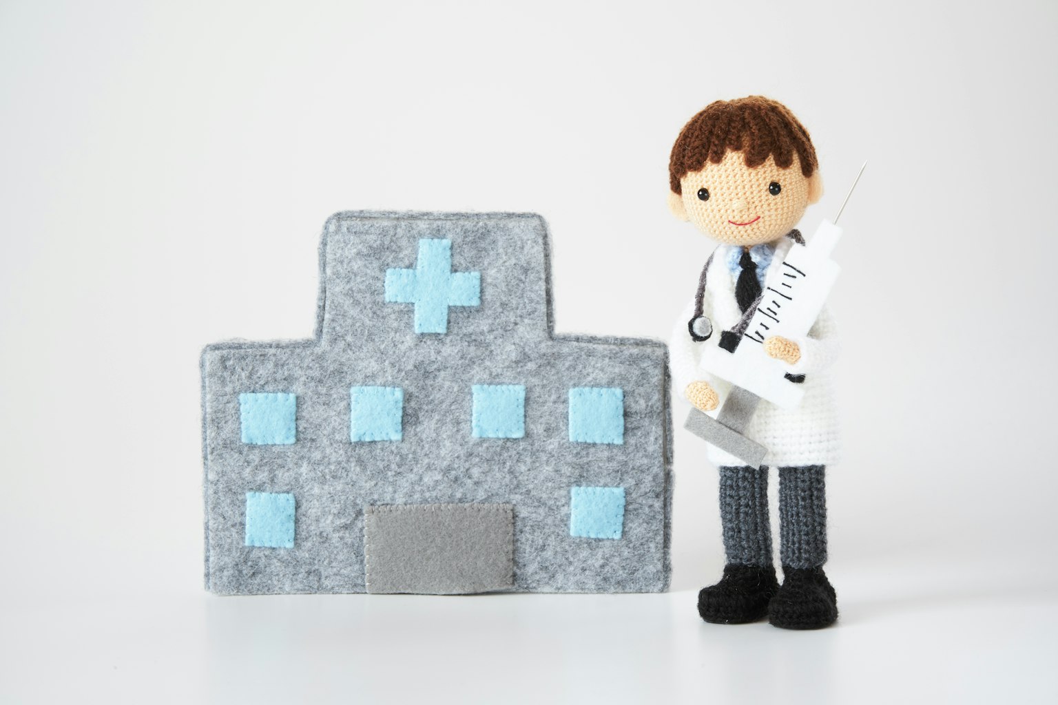 Một bức tượng bác sĩ nhỏ bên cạnh mô hình bệnh viện màu xám