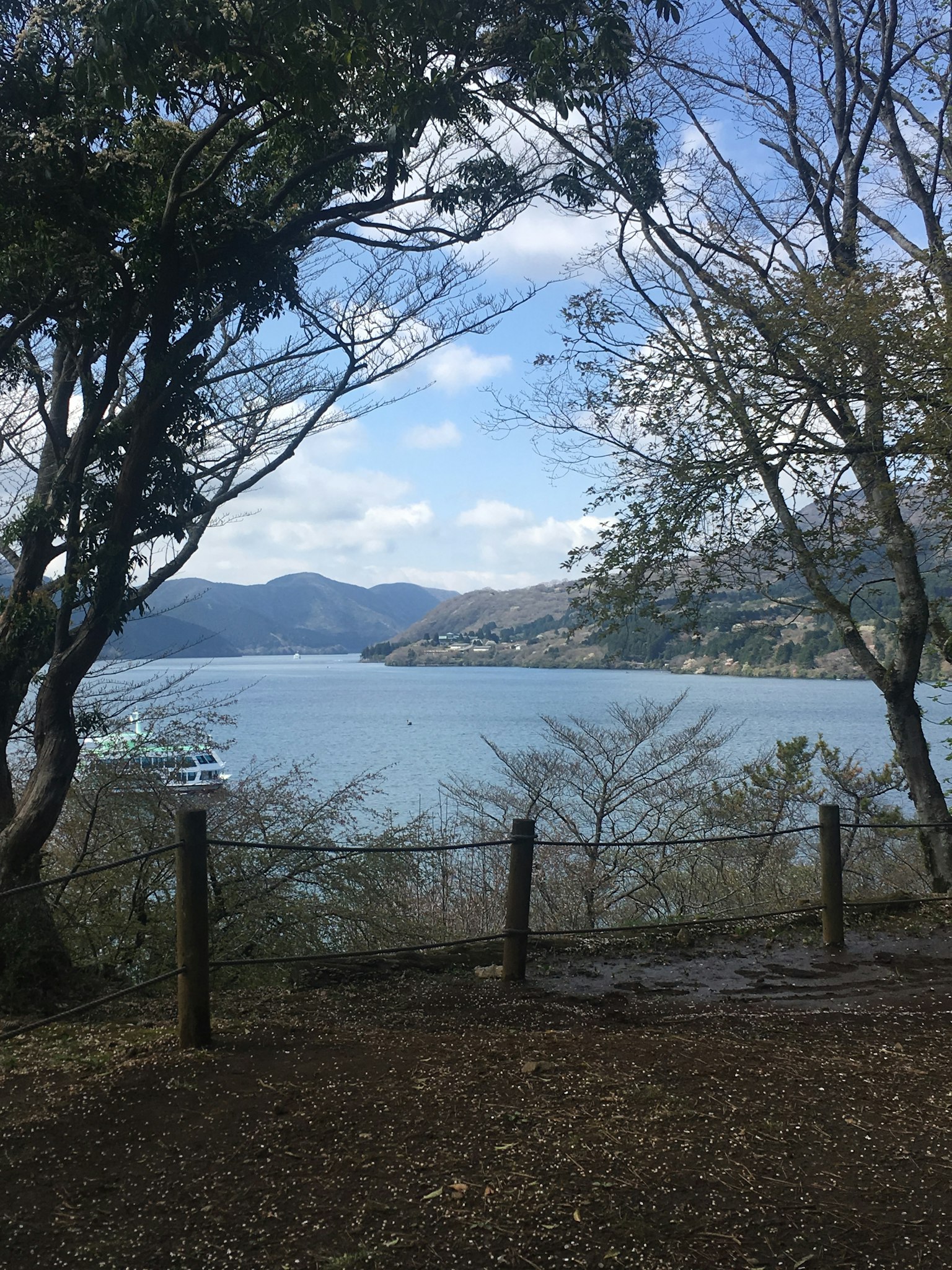 寧靜湖泊的風景，四周環繞著山脈和樹木，藍天白雲