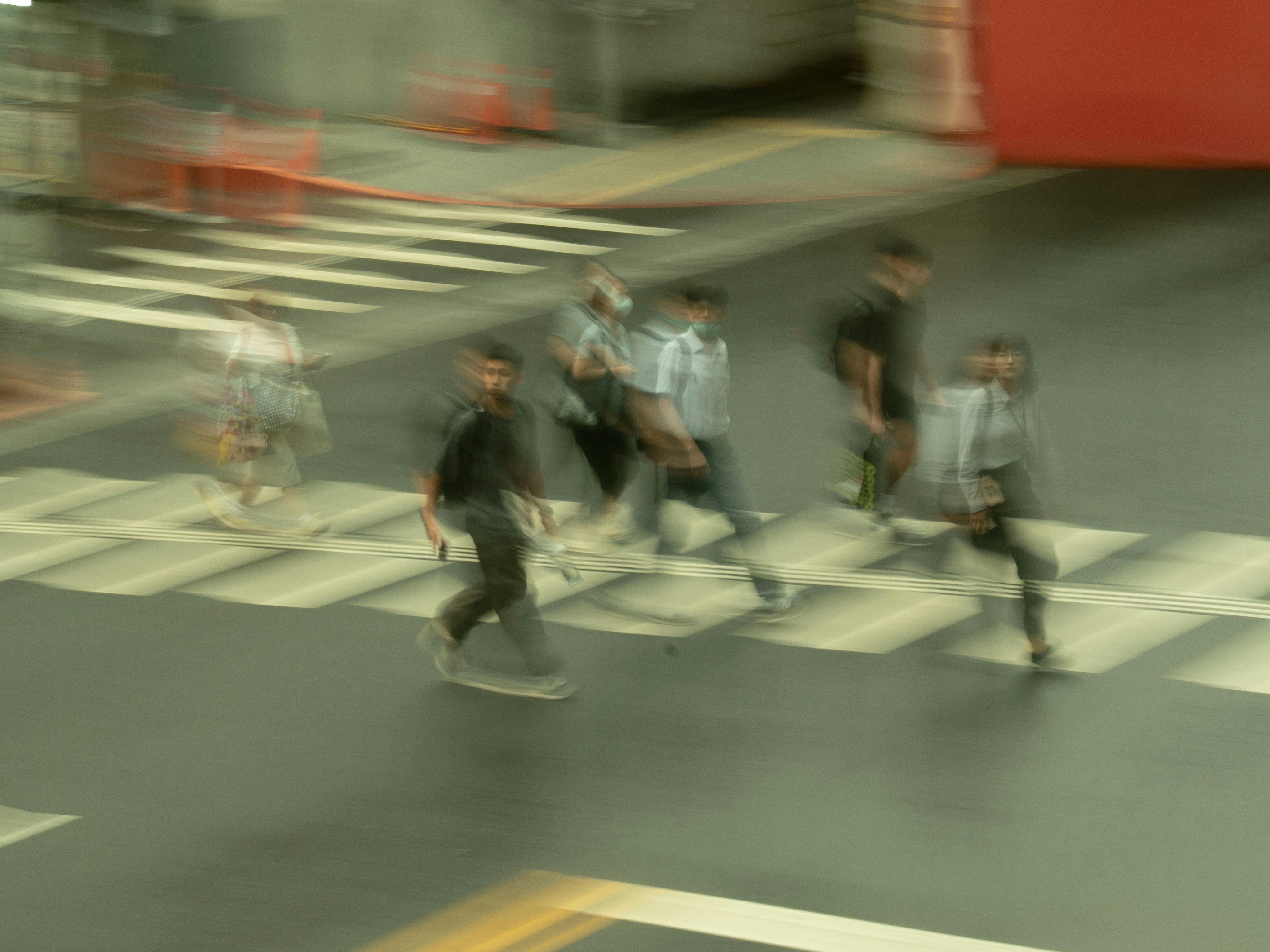 モーションブラーのある交差点で走る人々のストリートスナップ
