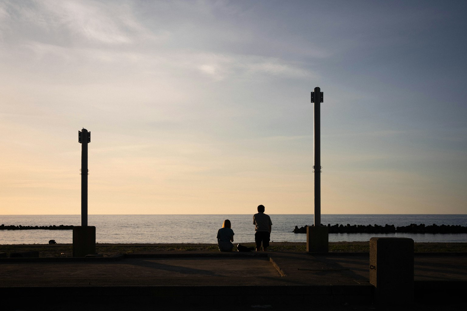 海辺のシルエットの人々と灯柱がある風景