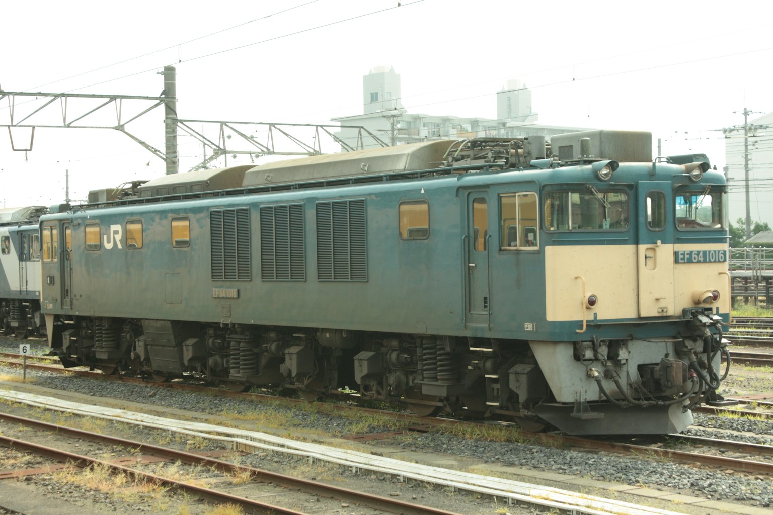 Locomotora eléctrica azul estacionada junto a las vías del tren