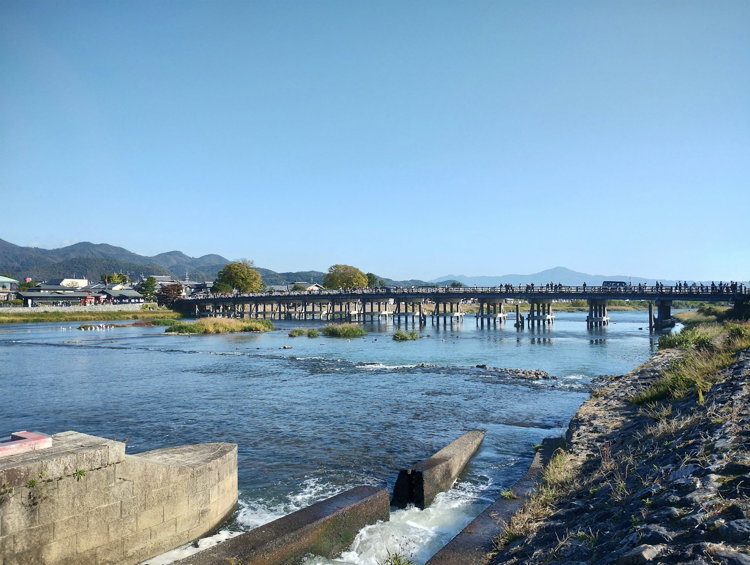 Scène de rivière sereine avec un pont montagnes en arrière-plan ciel bleu lumineux