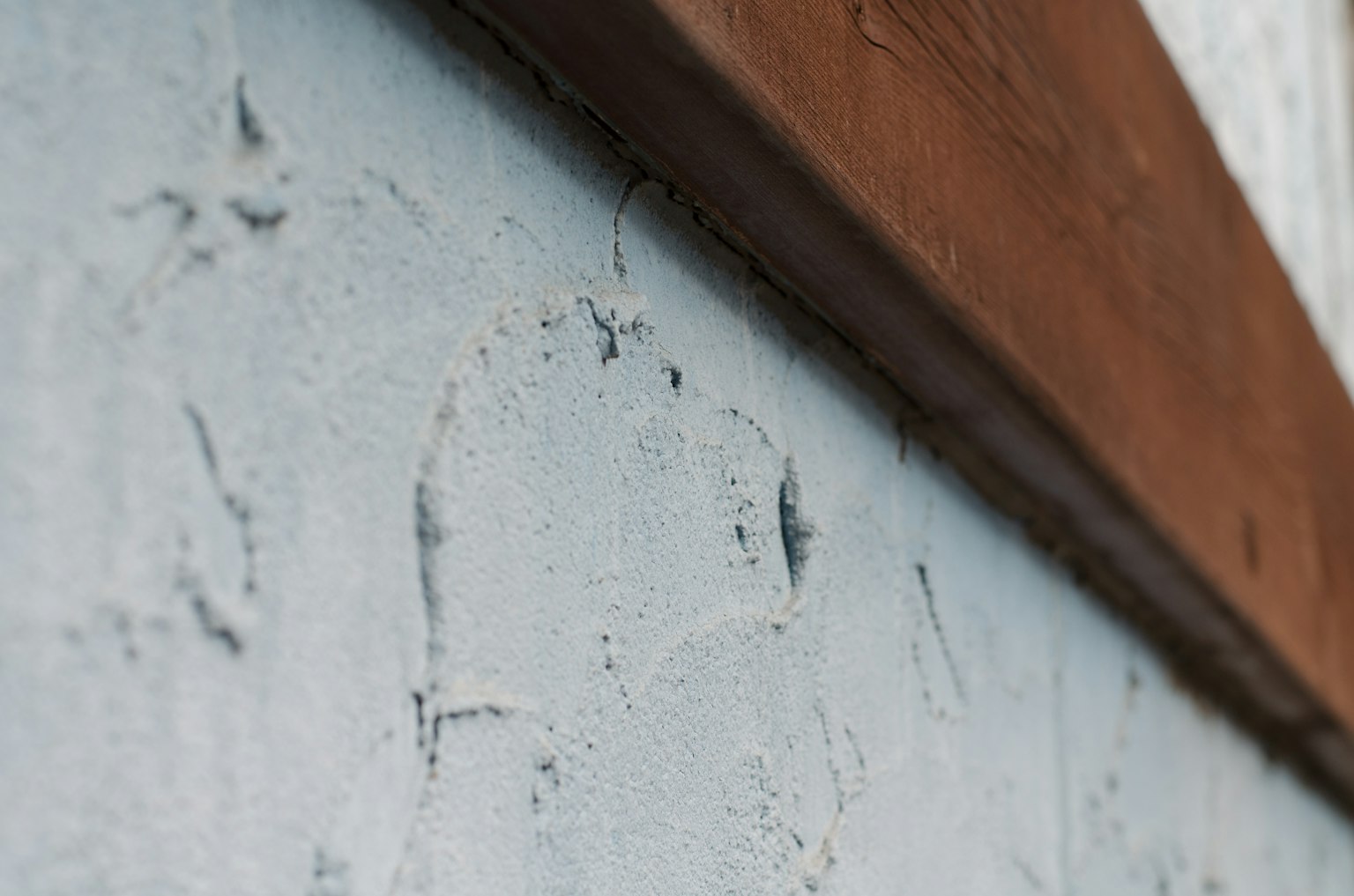 Acercamiento a una pared azul texturizada con una viga de madera