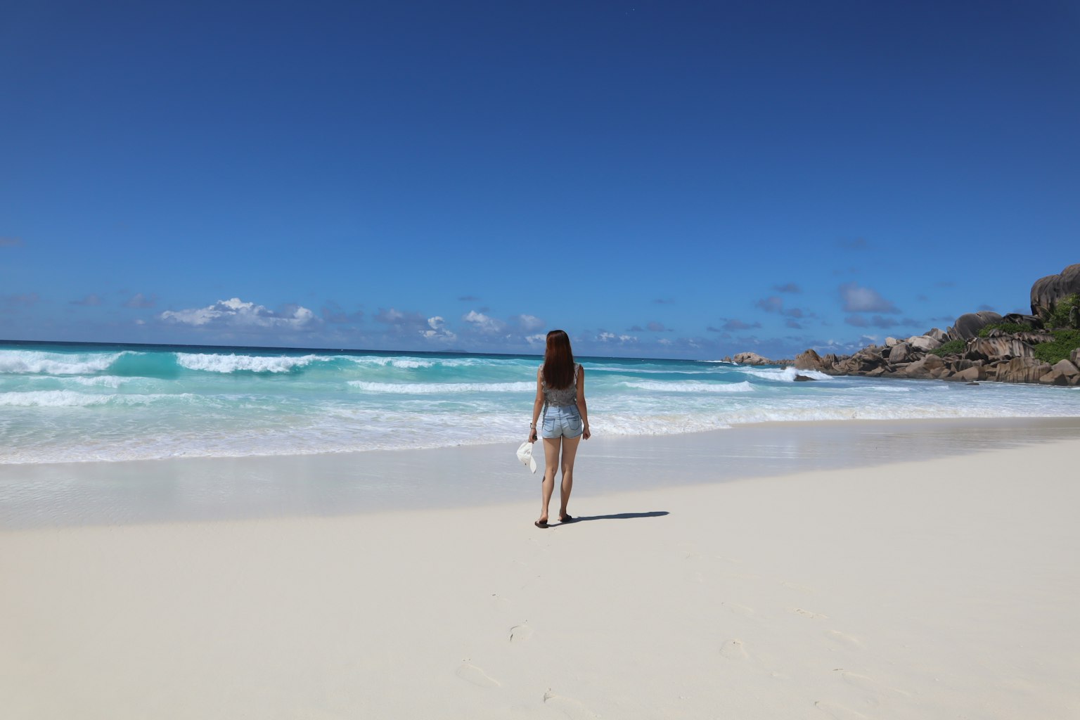 Une femme marchant sur une plage de sable blanc avec un océan bleu
