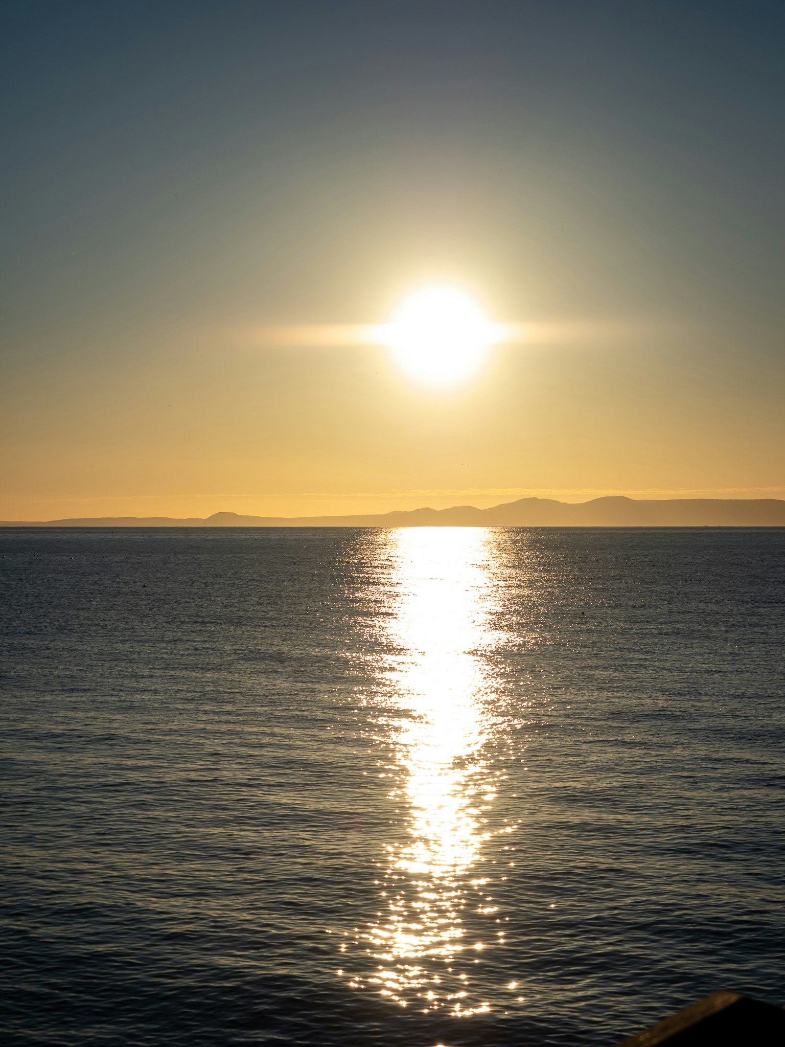 水平線に沈む夕日が照らす海面のきらめき