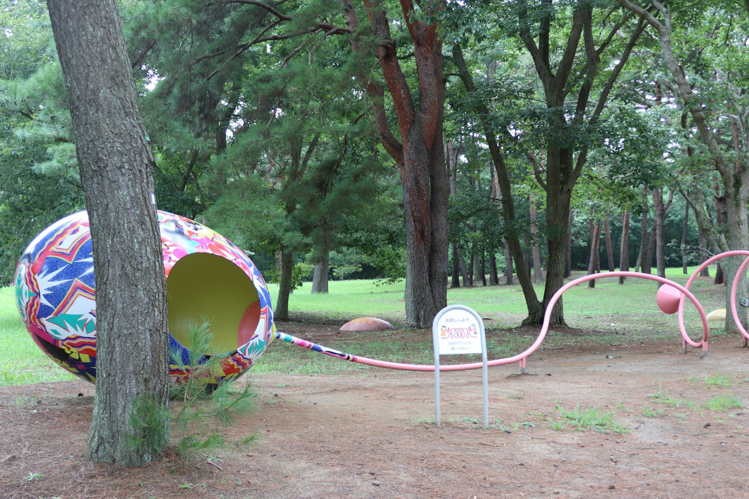 Structure de jeu en forme d'œuf coloré avec un long tube dans un parc