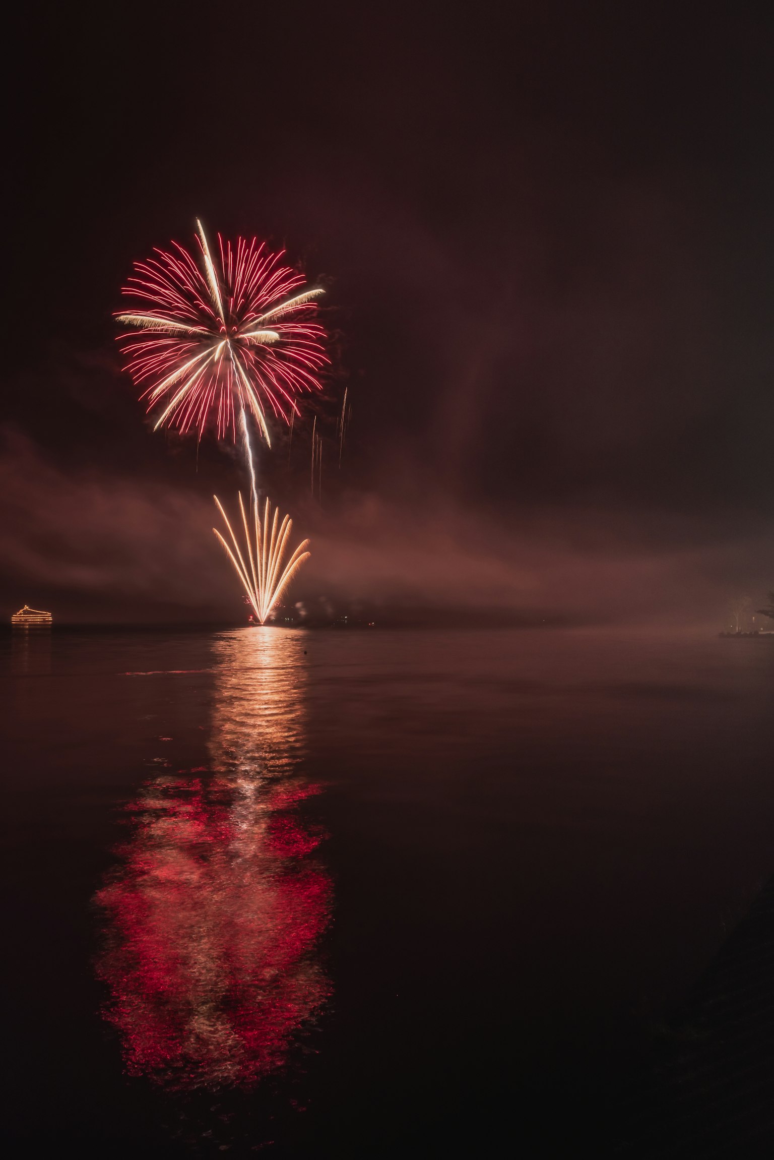 Beautiful moment of fireworks blooming in the night sky colorful reflections on the water