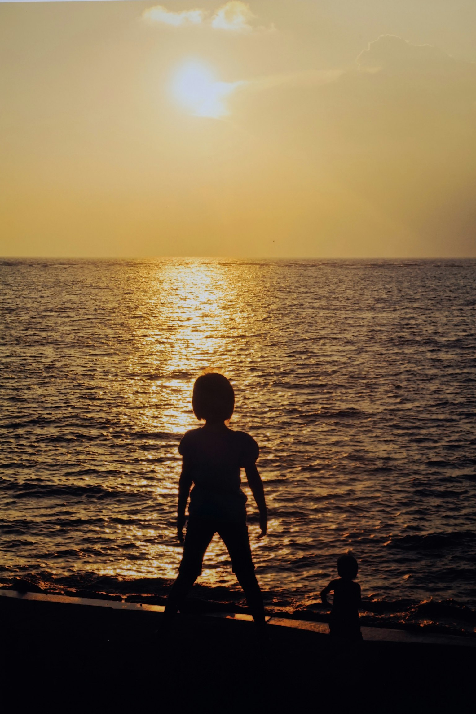 夕陽下海面上站著孩子的輪廓