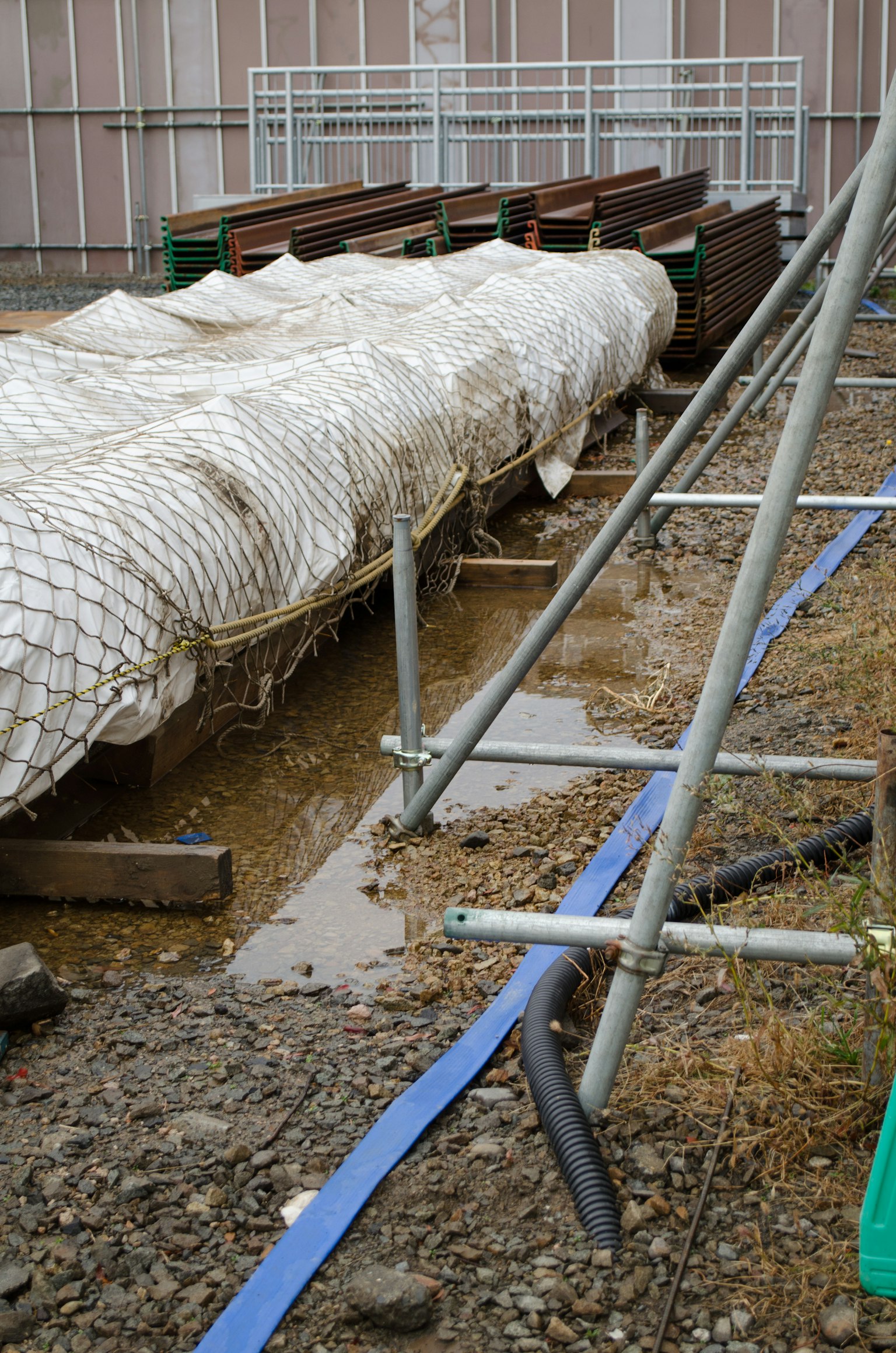 Construction site with a covered structure and puddles