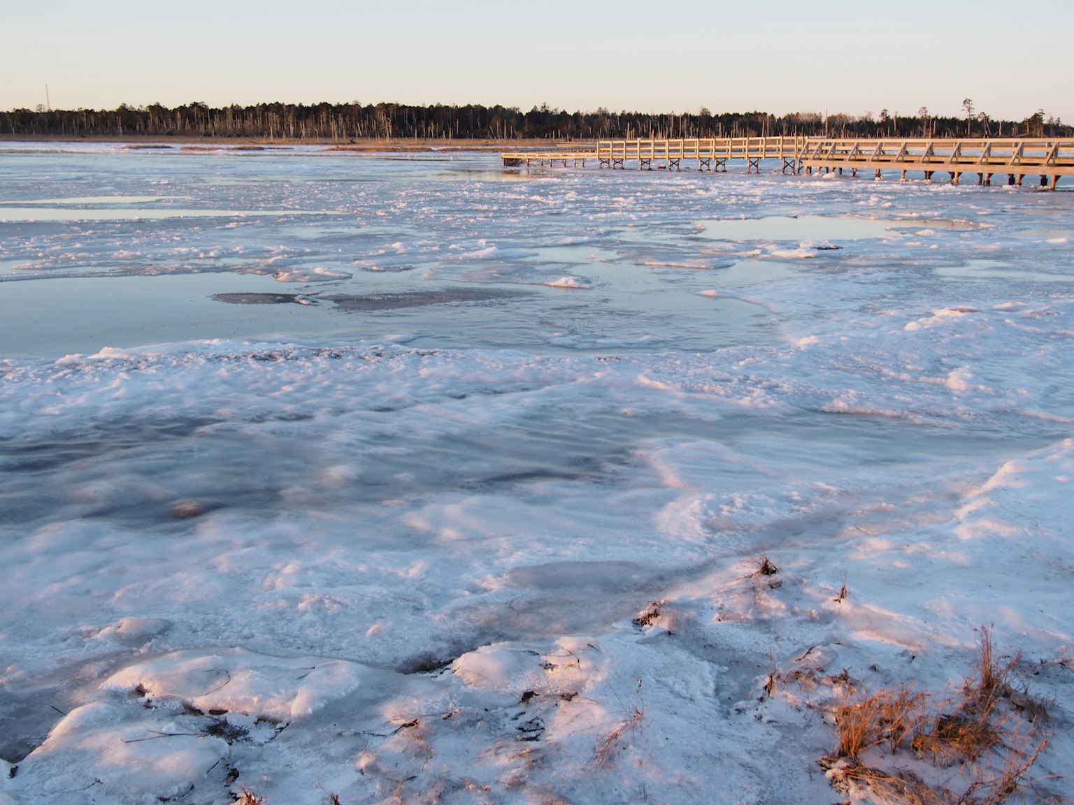 Gefrorene Seefläche mit Schnee bei Sonnenaufgang Reflektierendes Licht schafft eine ruhige Atmosphäre