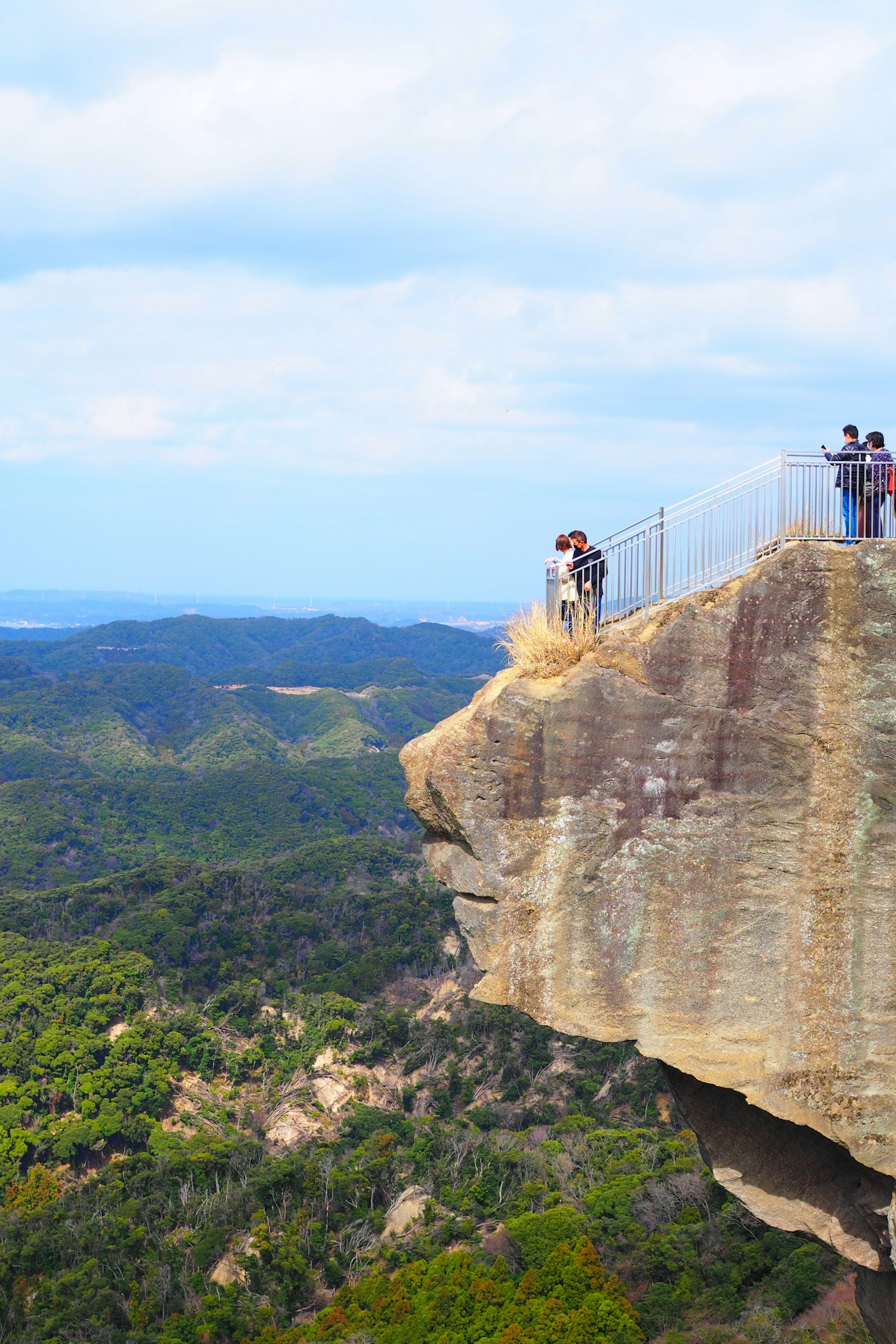 Personnes se tenant au bord d'une falaise avec de belles montagnes en arrière-plan