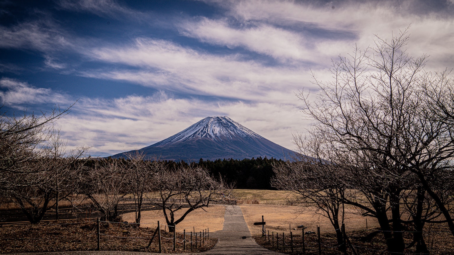 Gunung Fuji bersalju di bawah langit biru dengan awan yang tersebar