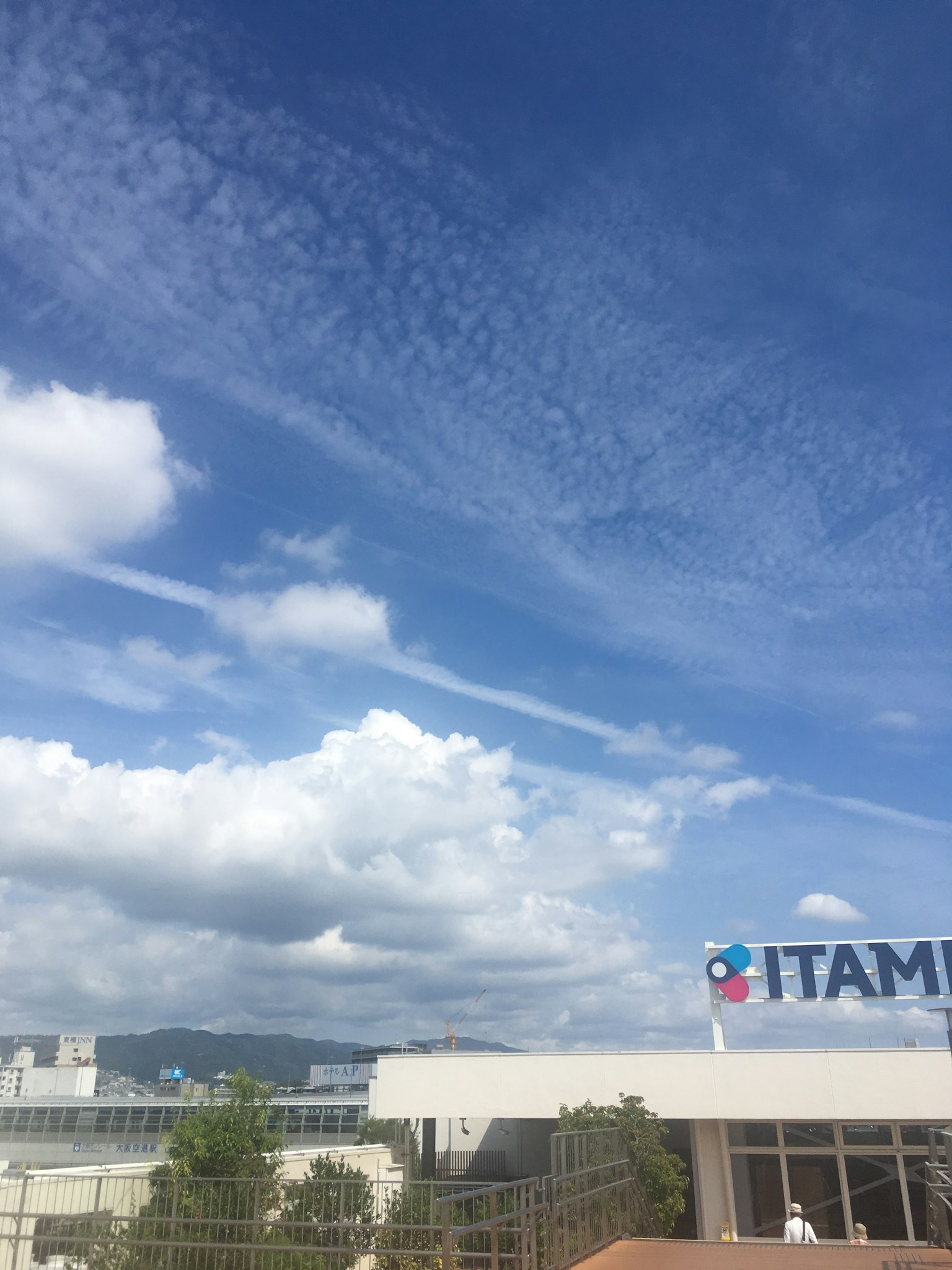 Cielo blu con nuvole bianche e il segno ITAMI visibile