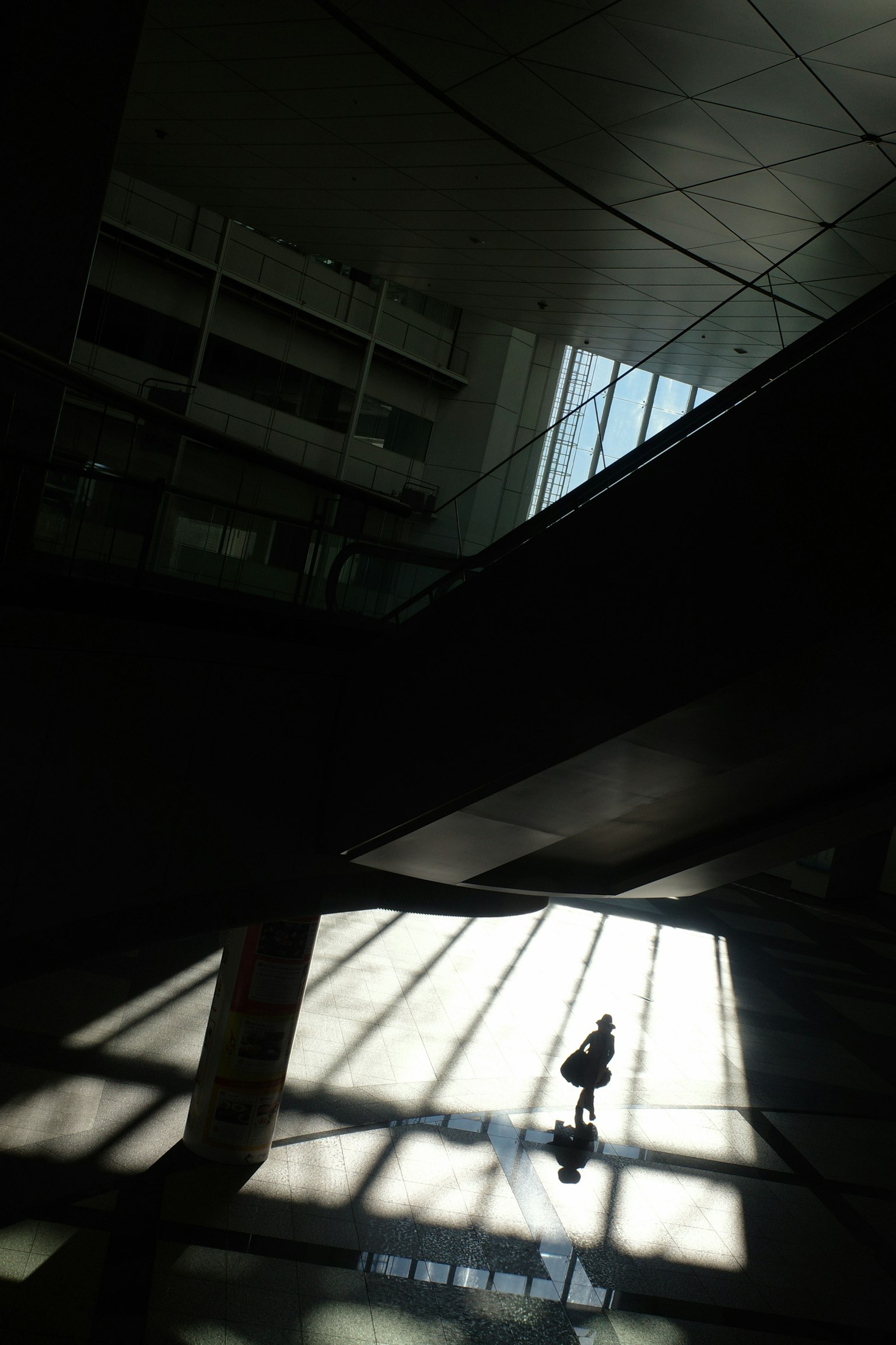 Ein Innenraum mit abstrakten Mustern aus Schatten und Licht, in dem eine Person geht