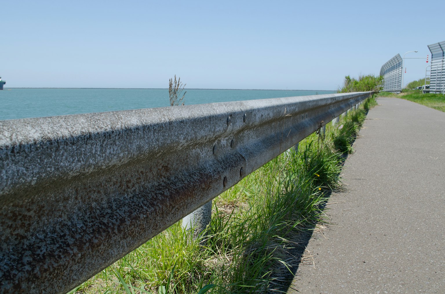 Metal guardrail near a paved walkway by the seaside