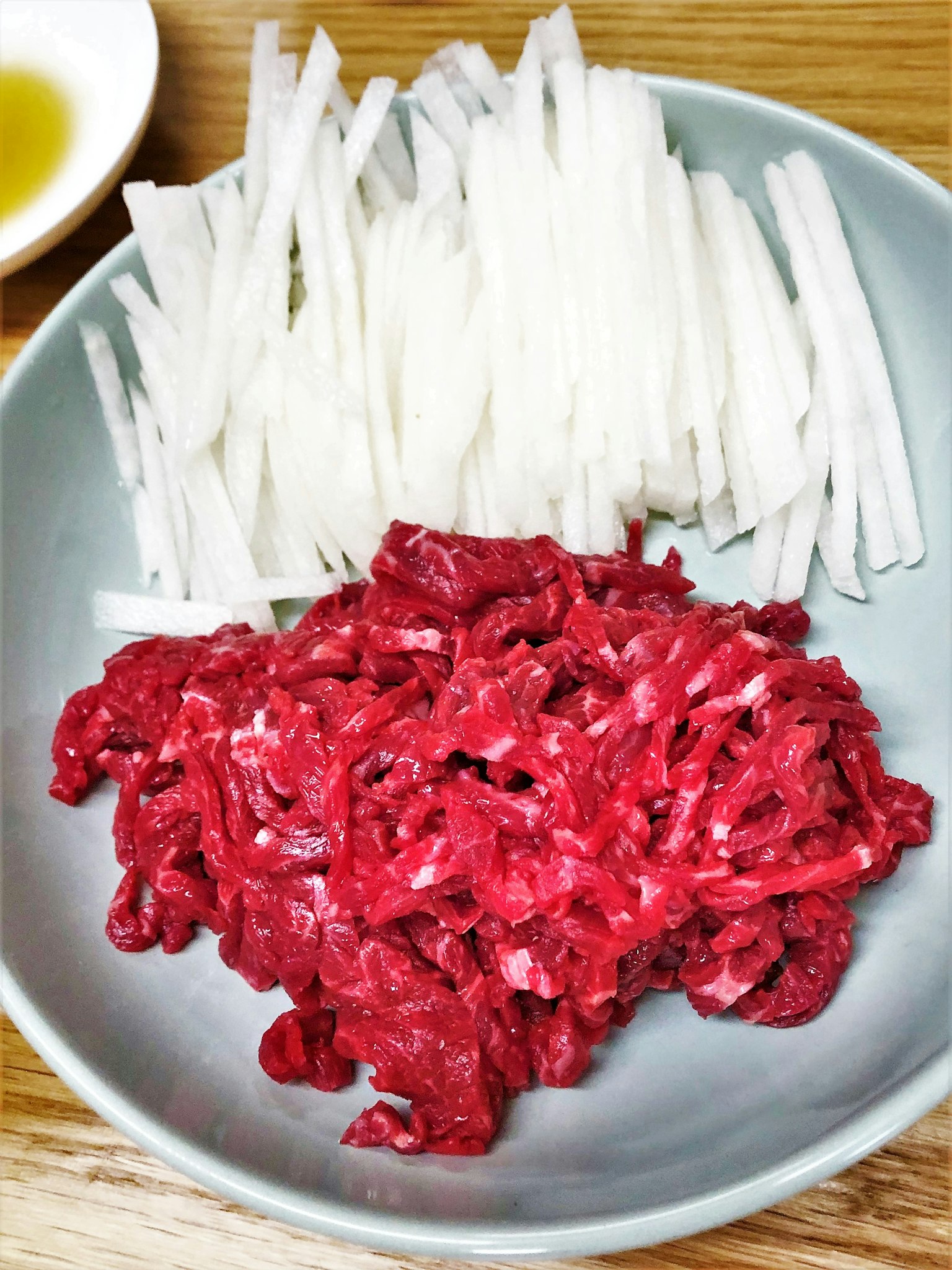A plate with sliced white radish and minced red beef