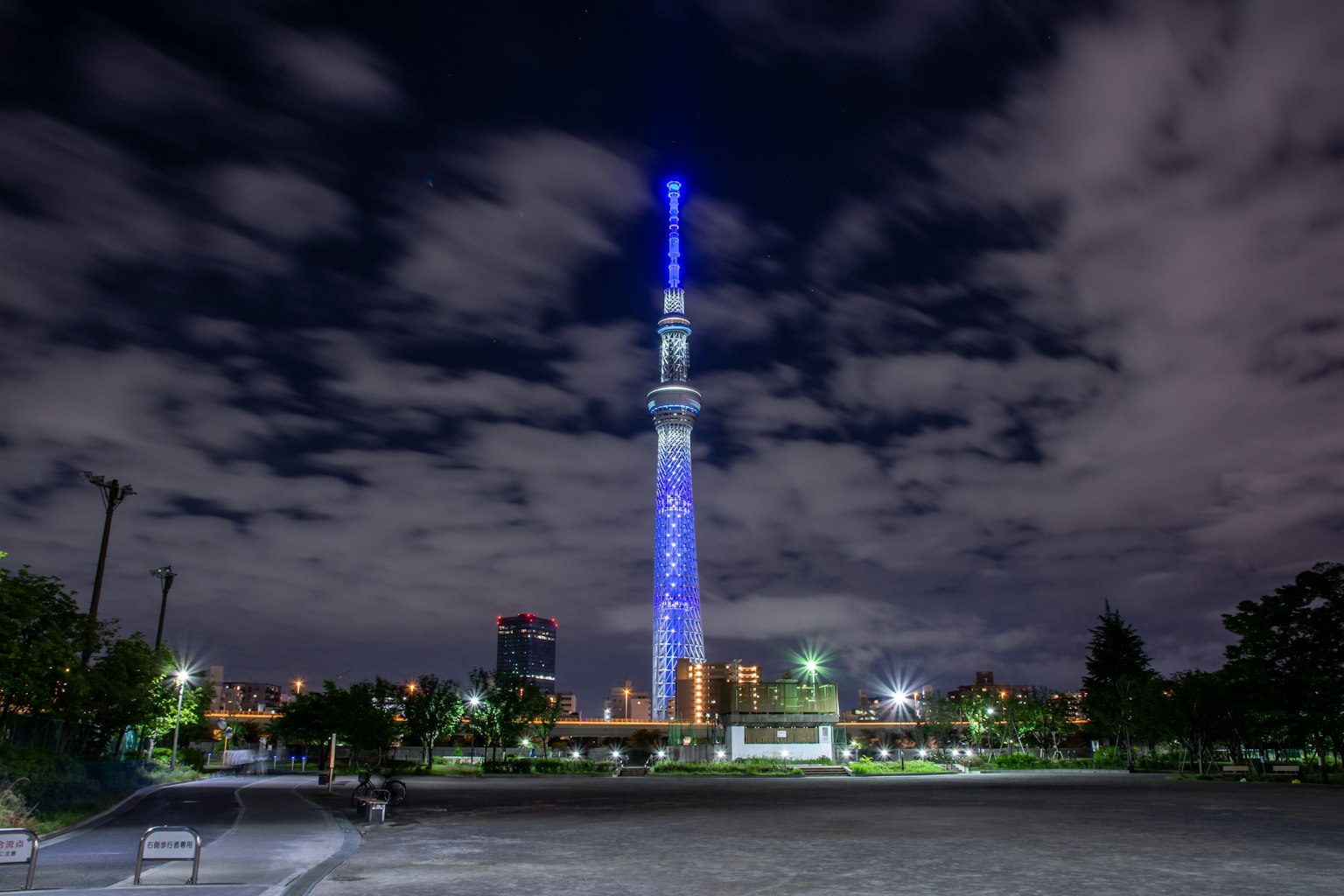 Tokyo Skytree bei Nacht in Blau beleuchtet umgeben von Wolken
