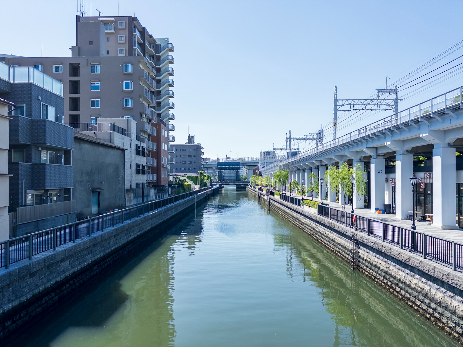 Paysage urbain le long d'une rivière avec une voie ferrée surélevée