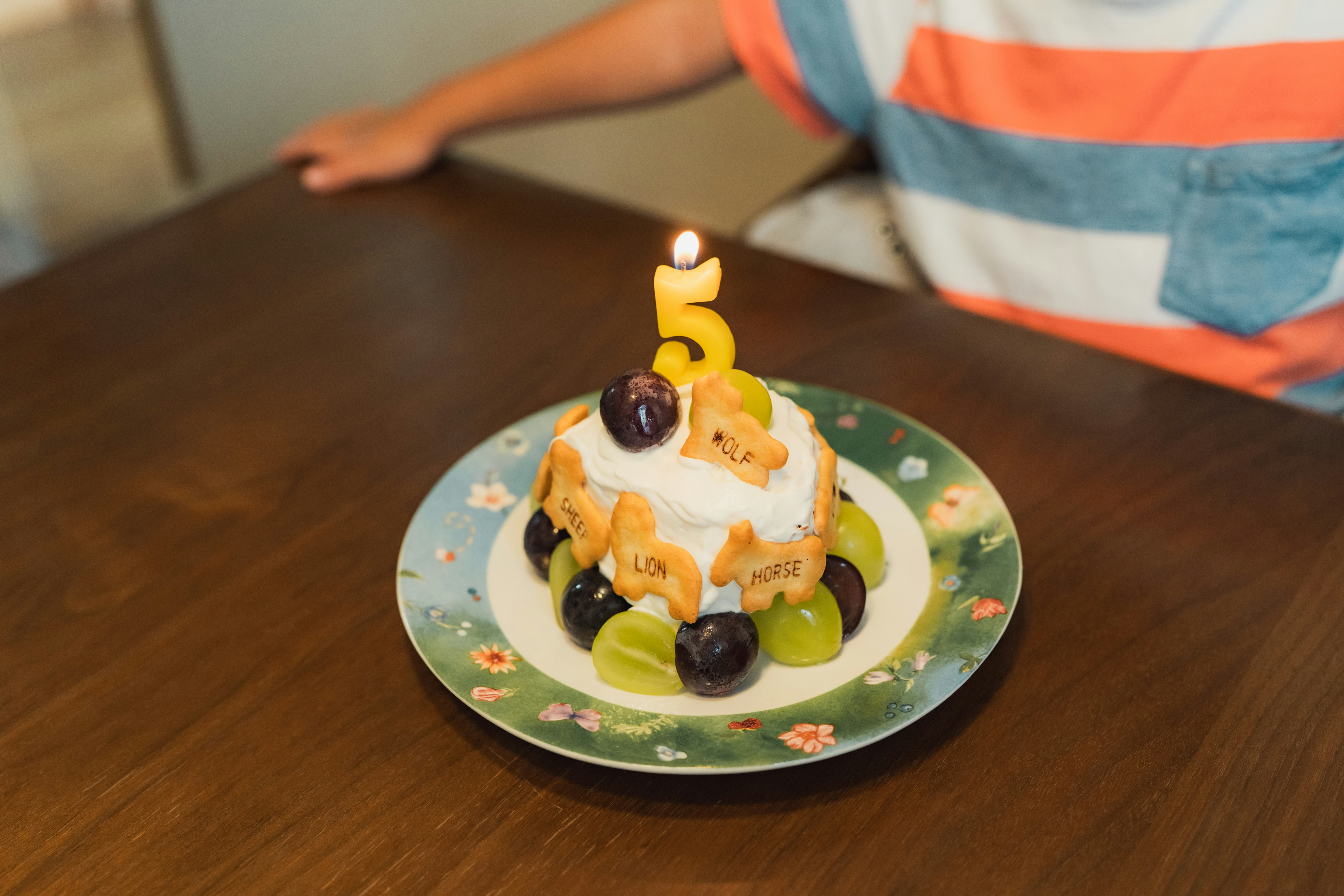 誕生日ケーキの上の5のろうそくとフルーツ