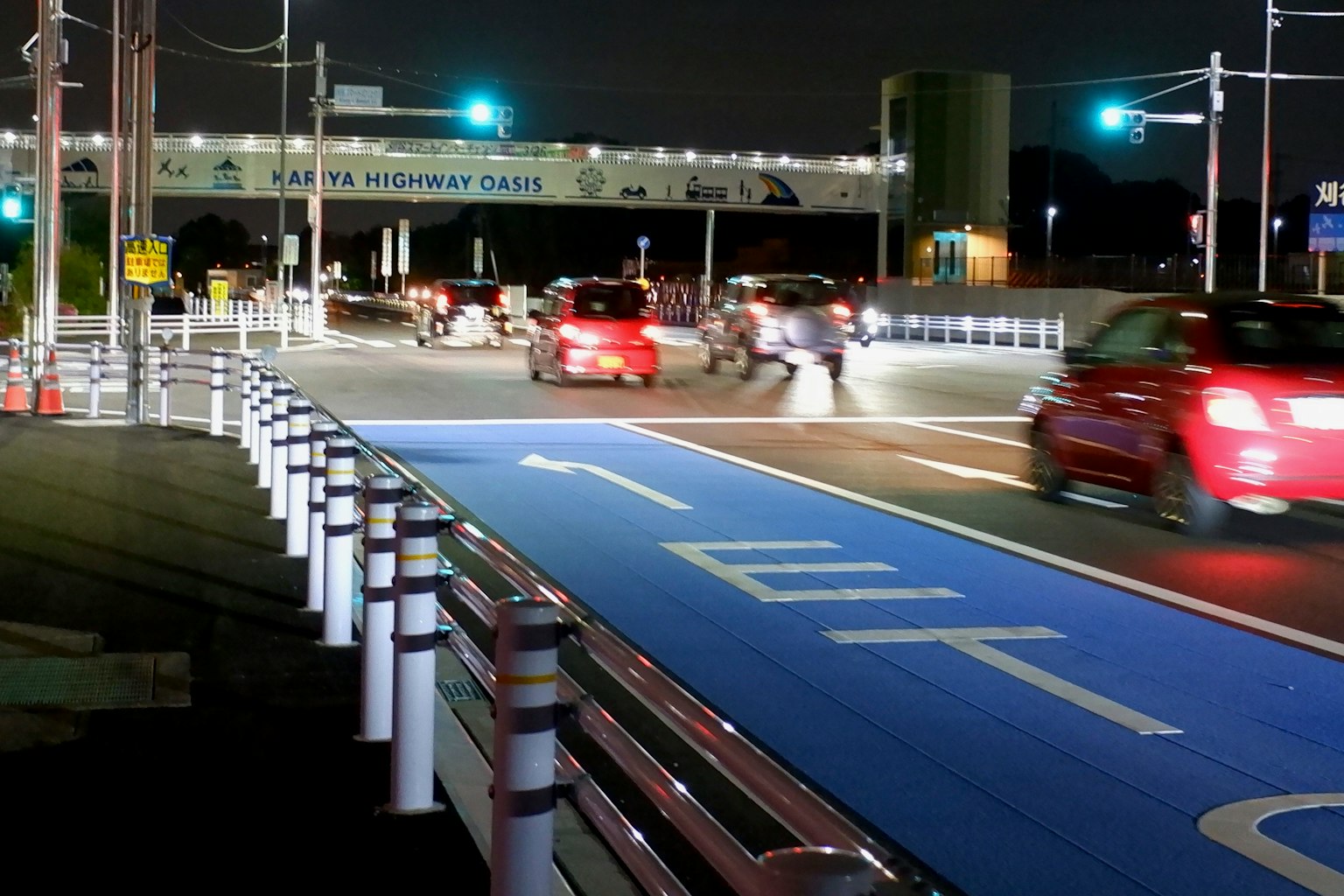 Nighttime intersection featuring a blue bike lane and traffic signals