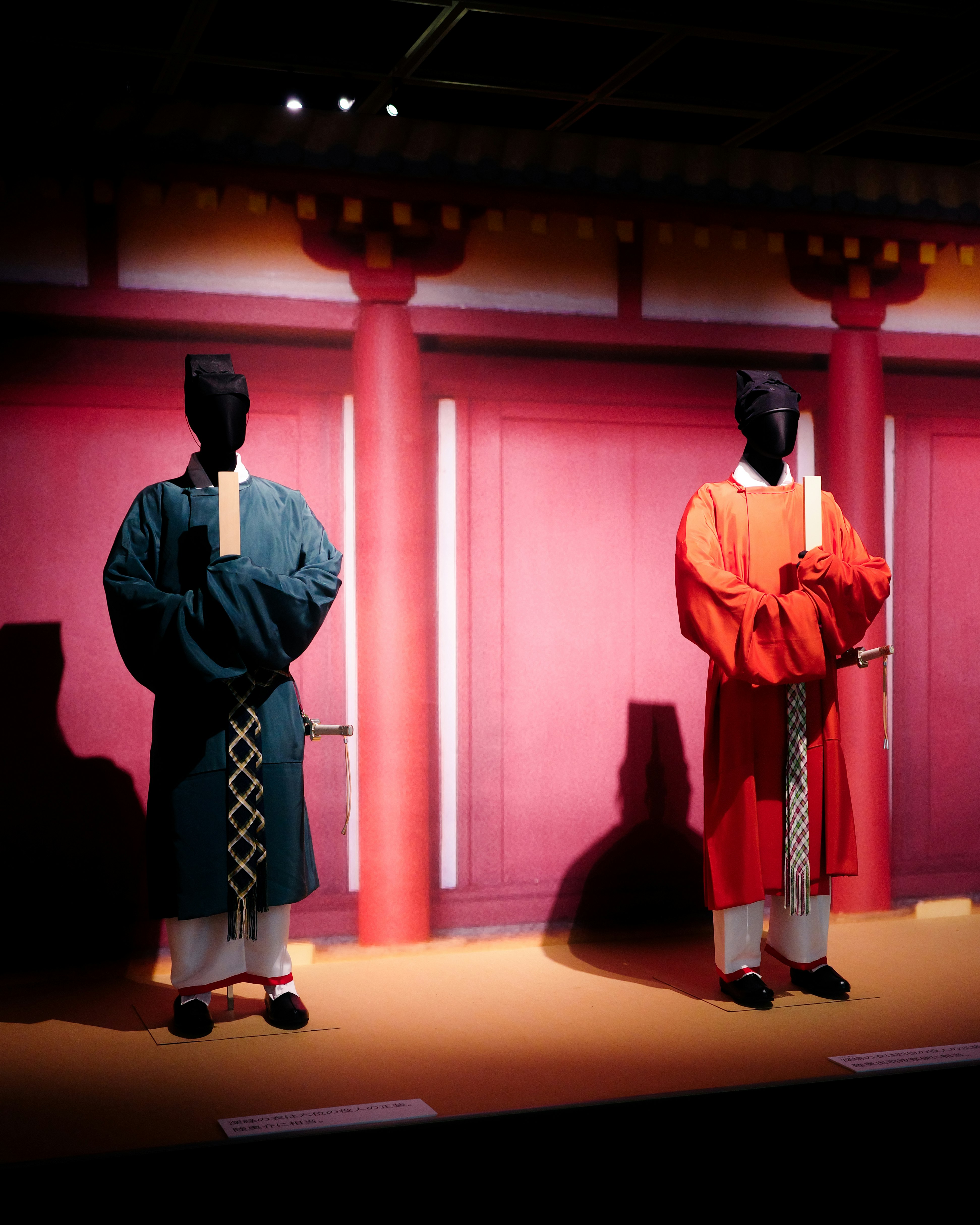 Personnages en kimono, style mannequins, debout devant un mur rouge vermillon