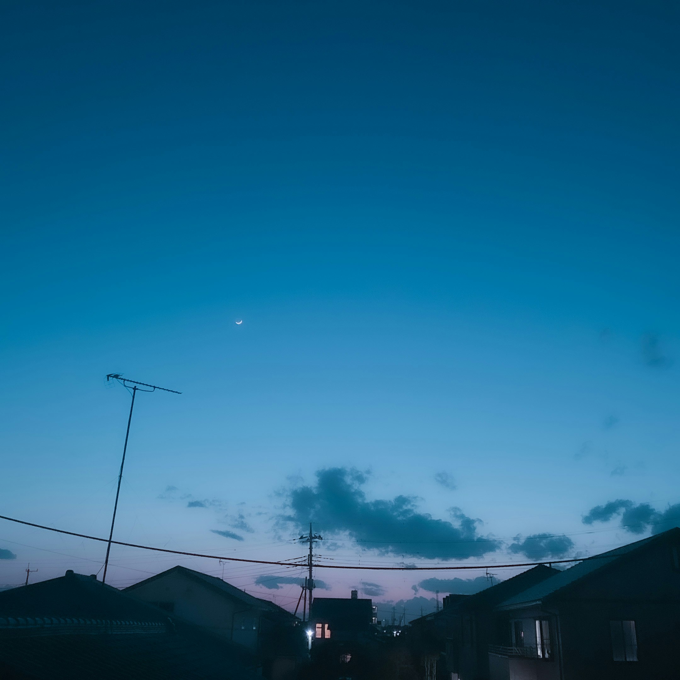 夕暮れの空に電線と家並みが広がる住宅街の風景