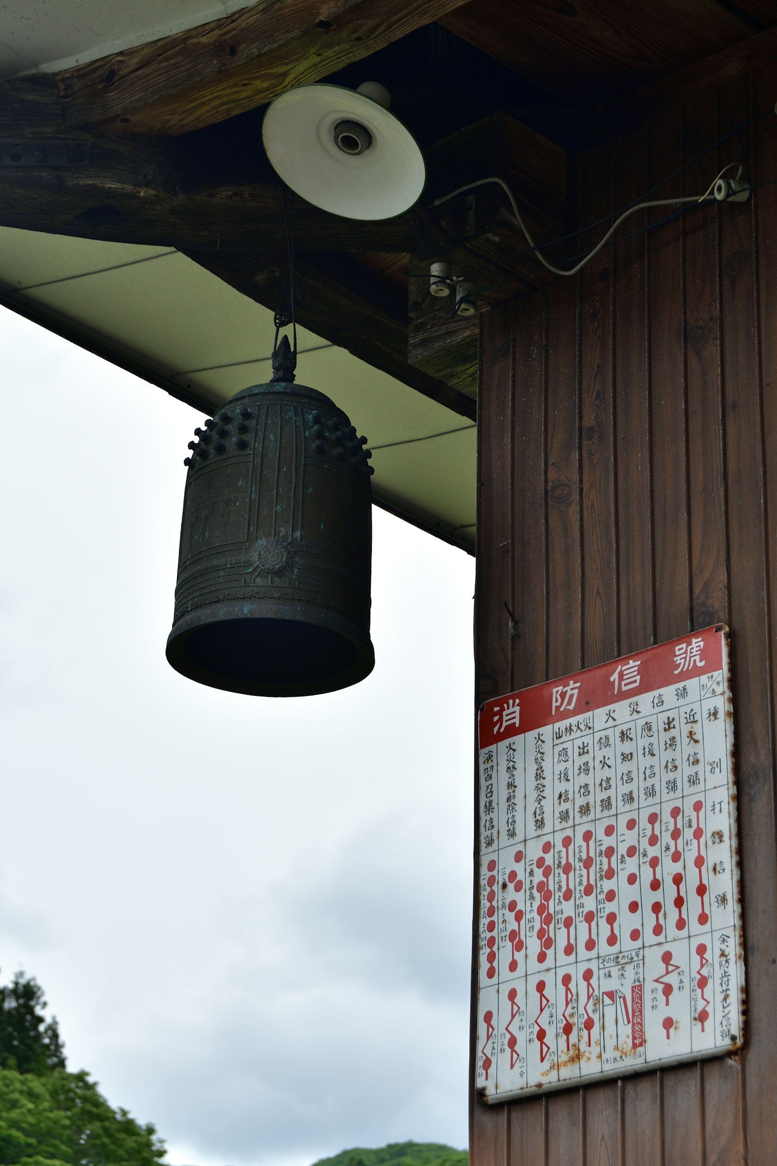 Una vecchia campana appesa a un palo di legno con un calendario attaccato