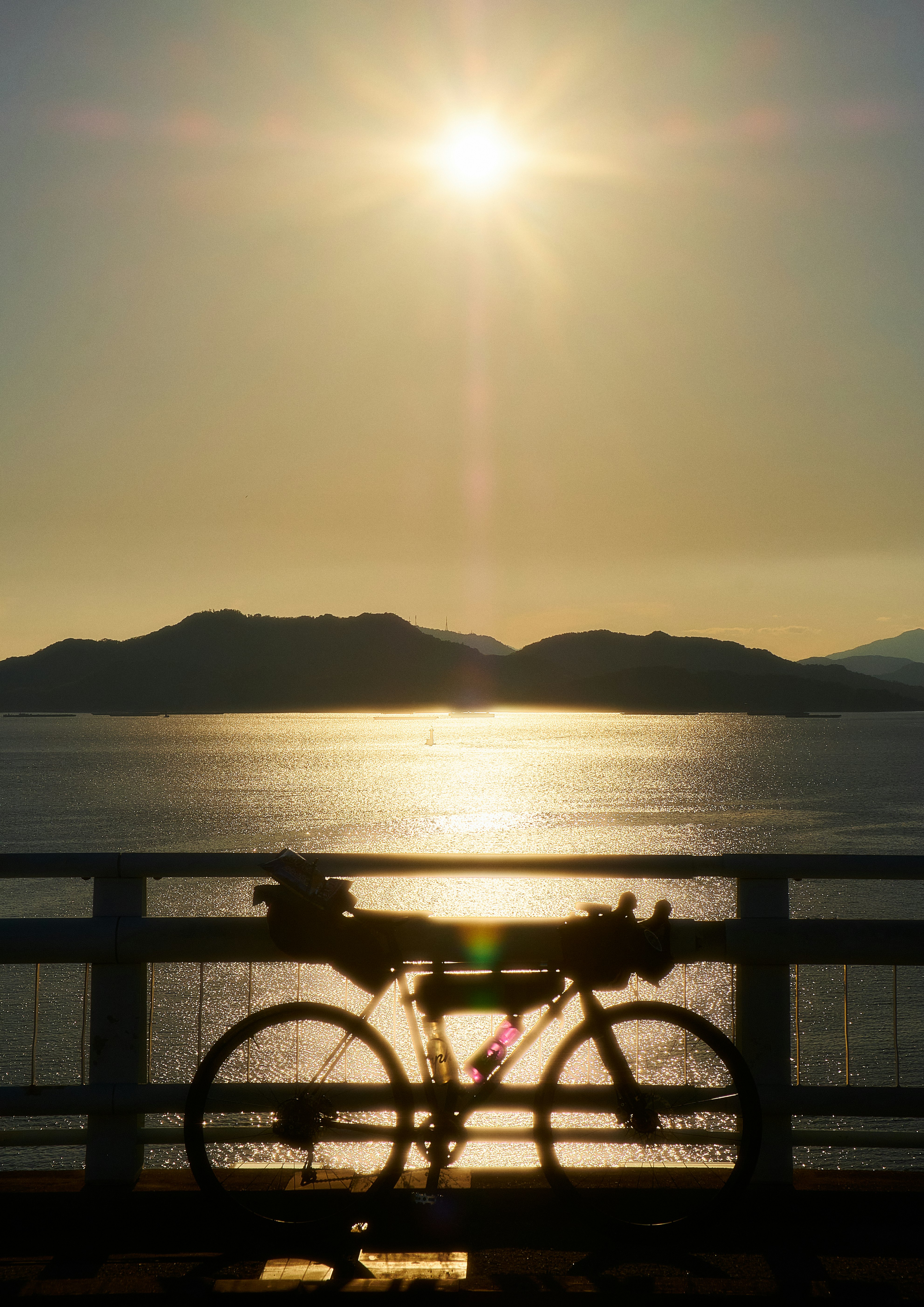 夕日を背景にした自転車のシルエットと静かな水面
