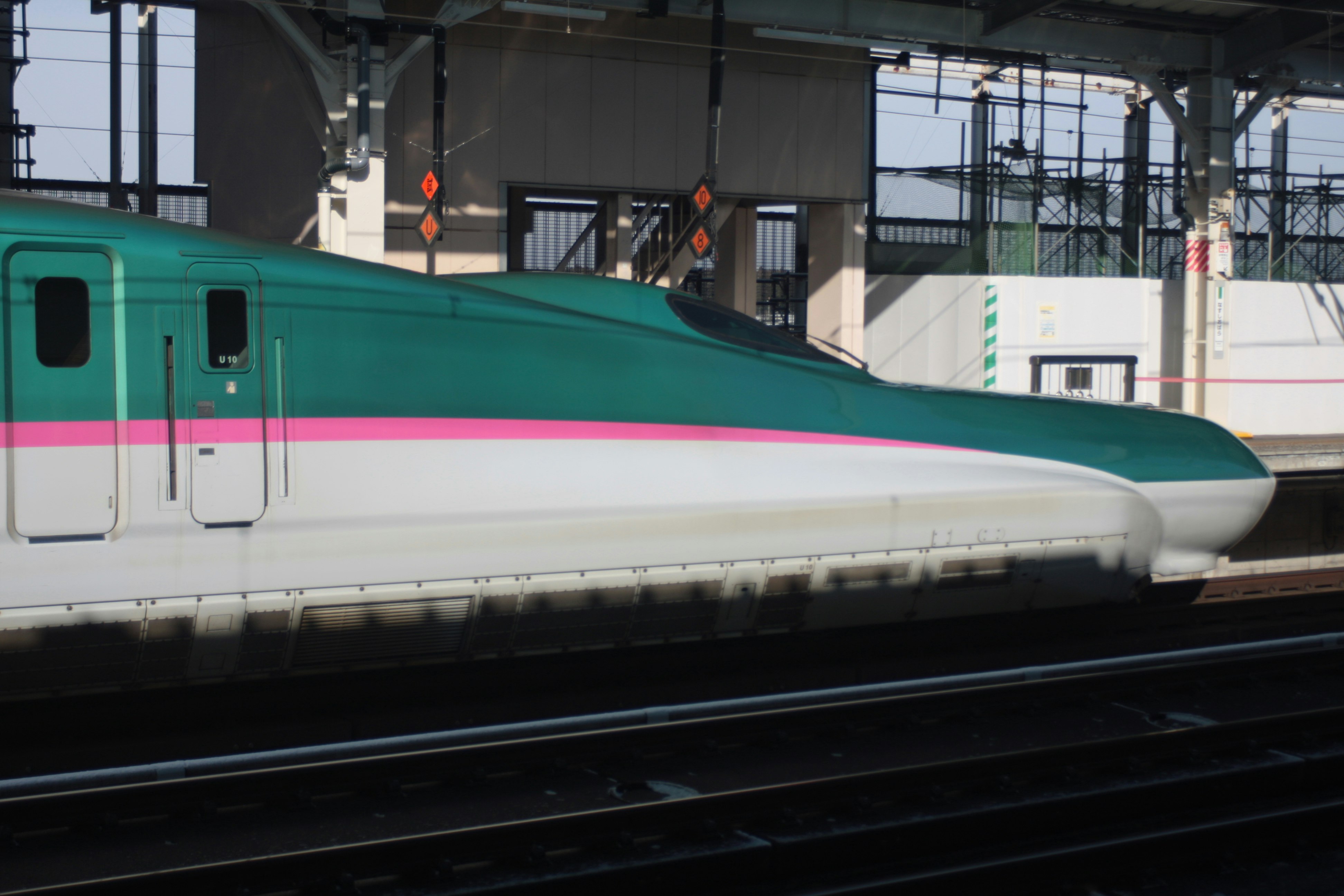 高架の線路を走る緑とピンクの電車