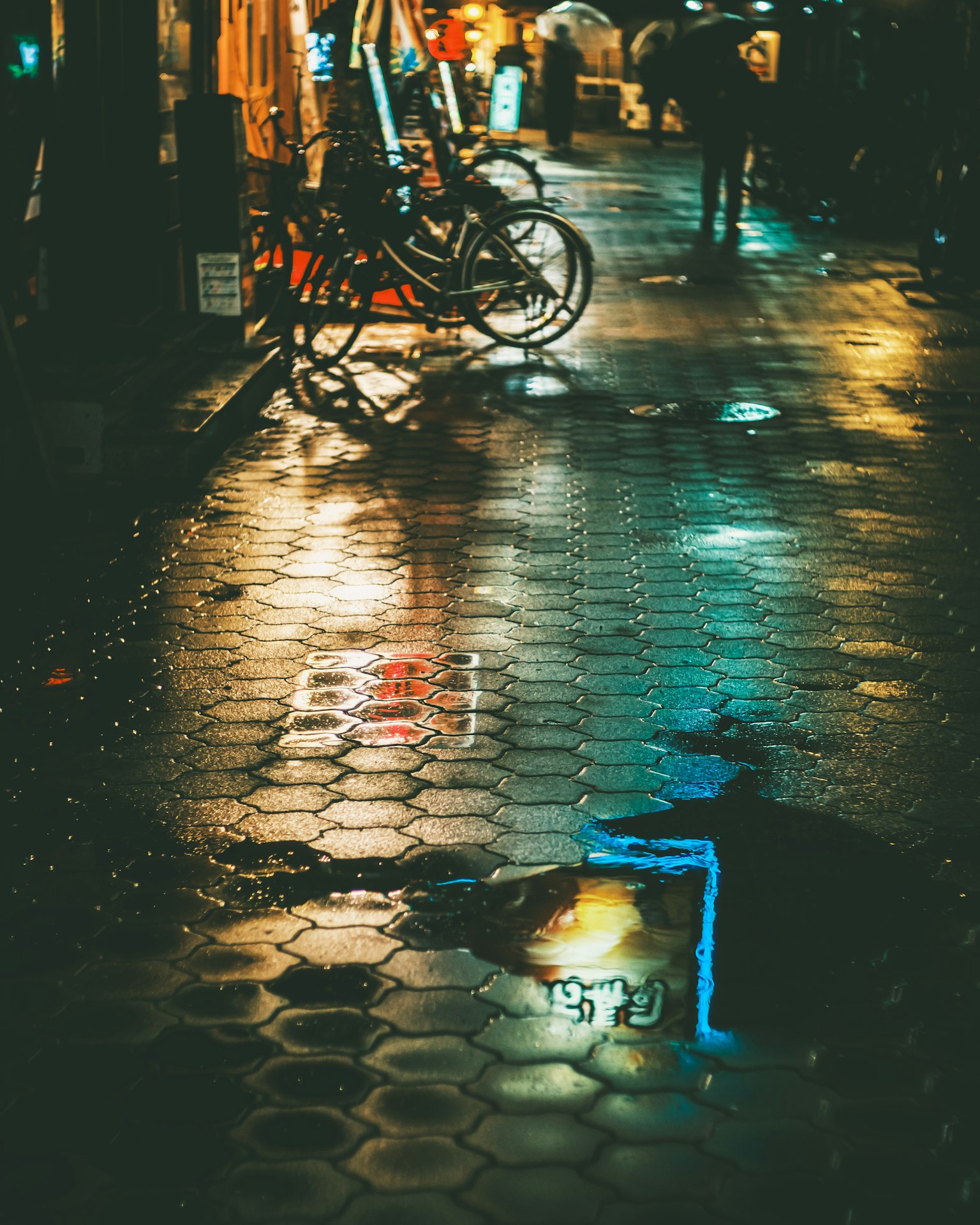 Camino de adoquines empapado por la lluvia que refleja luces de neón y una bicicleta