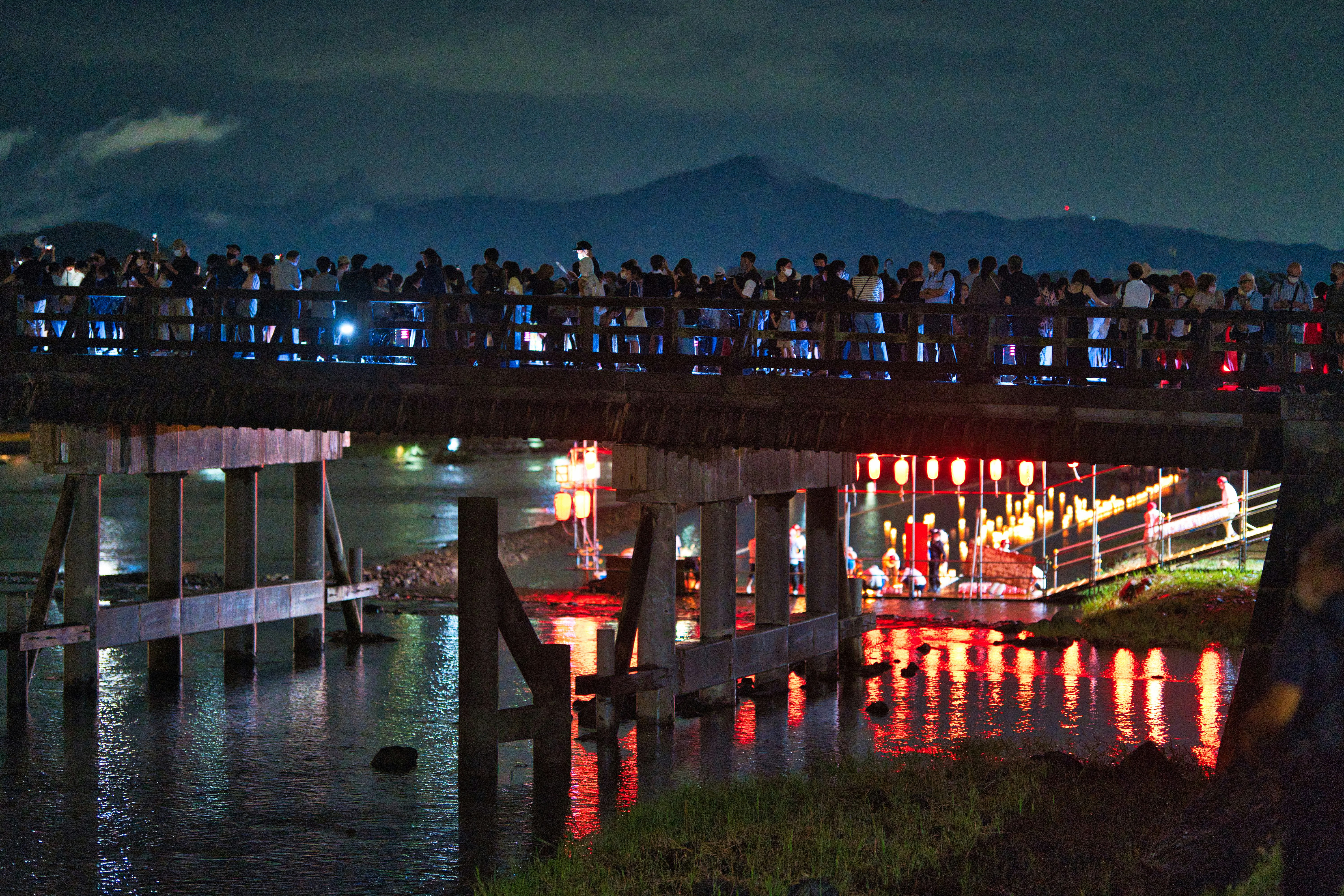 渡月橋の周辺で灯籠流しが行われる夜の嵐山の川沿い