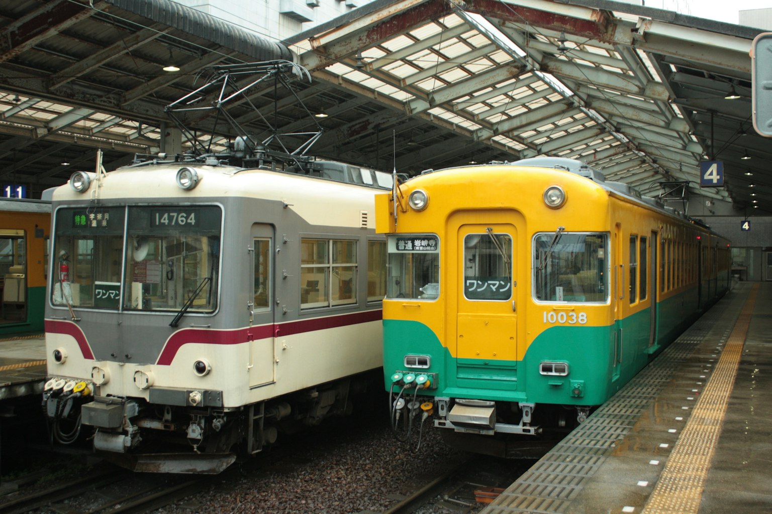 Dos trenes estacionados en una estación japonesa con colores distintivos