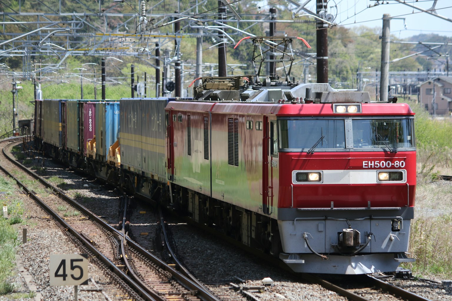 Locomotora eléctrica roja tirando un tren de carga en vías curvas