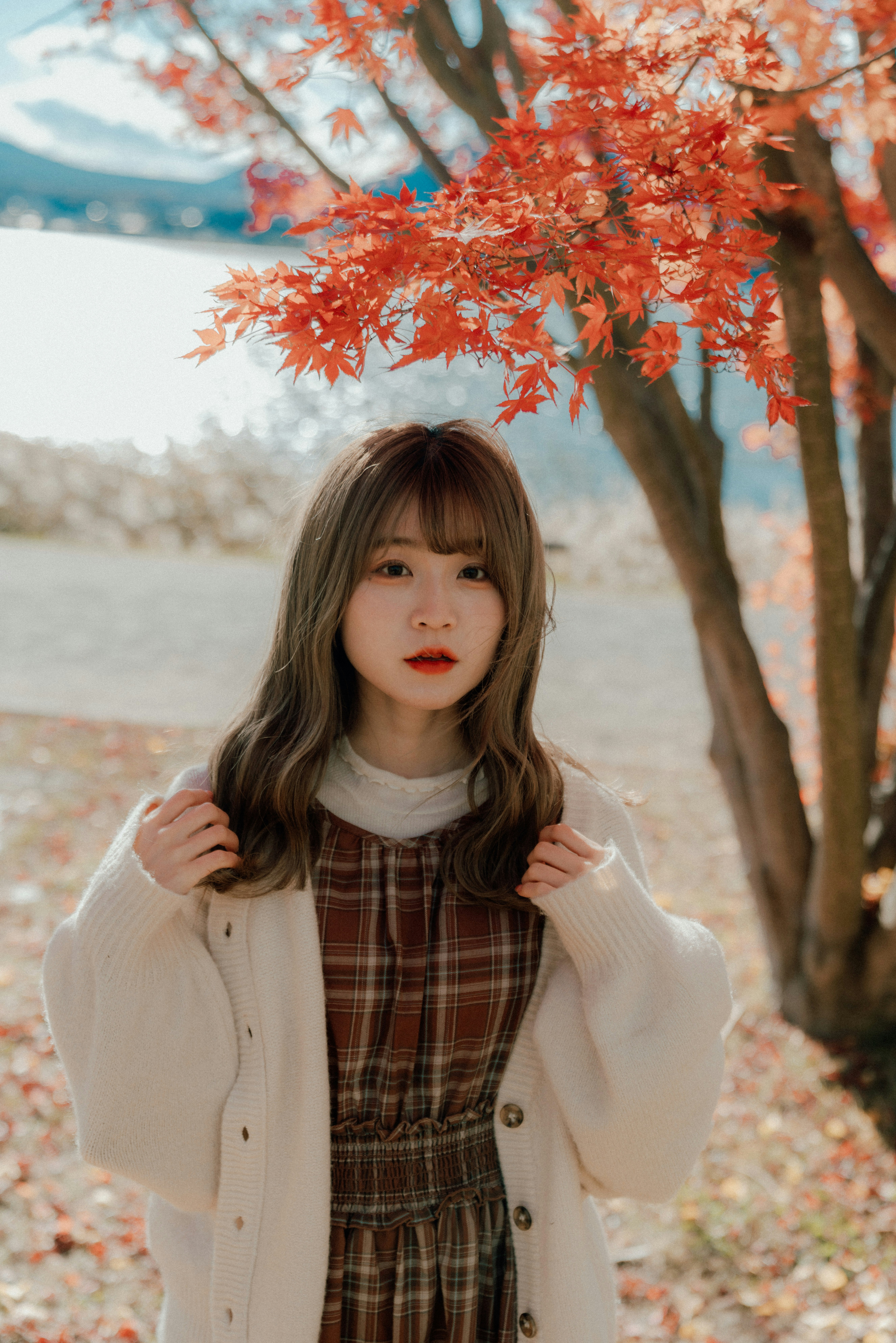 秋葉楓樹旁微笑的女性
